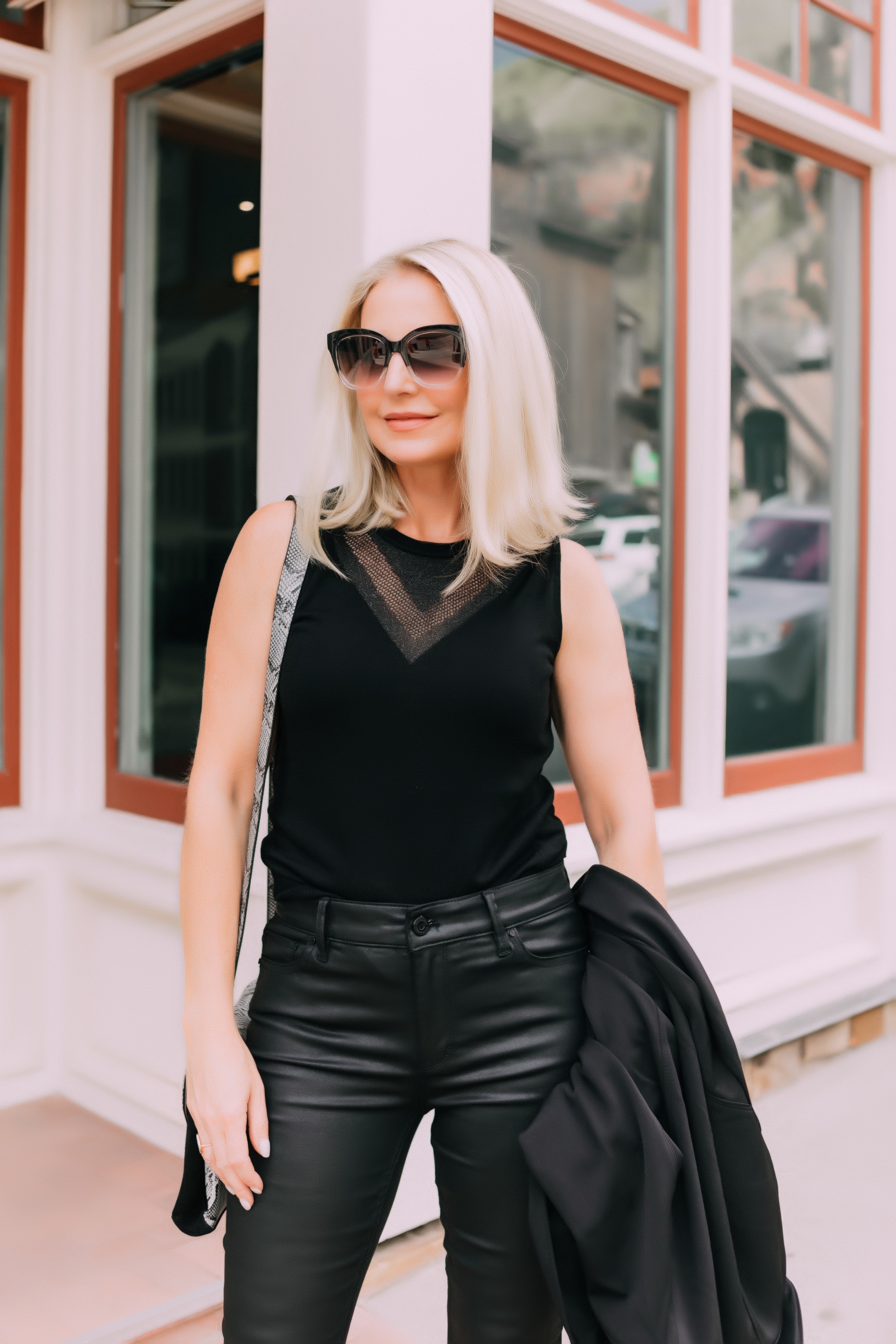 Coated Jeans, Fashion blogger Erin Busbee of BusbeeStyle.com wearing a head to toe all-black look by White House Black Market including coated jeans, python accented bag and heels, sleeveless sweater, and black blazer in Telluride, CO