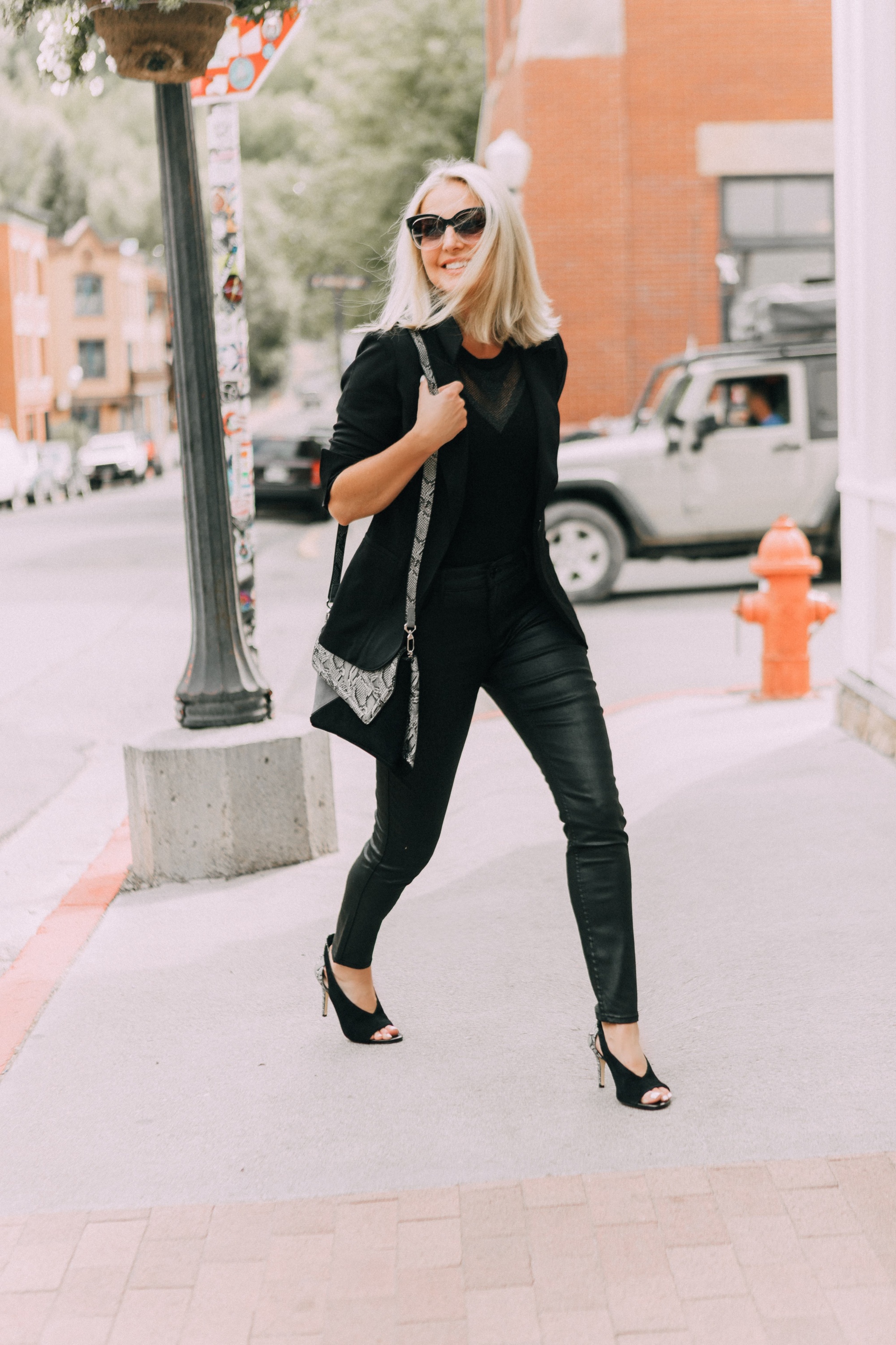 Coated Jeans, Fashion blogger Erin Busbee of BusbeeStyle.com wearing a head to toe all-black look by White House Black Market including coated jeans, python accented bag and heels, sleeveless sweater, and black blazer in Telluride, CO