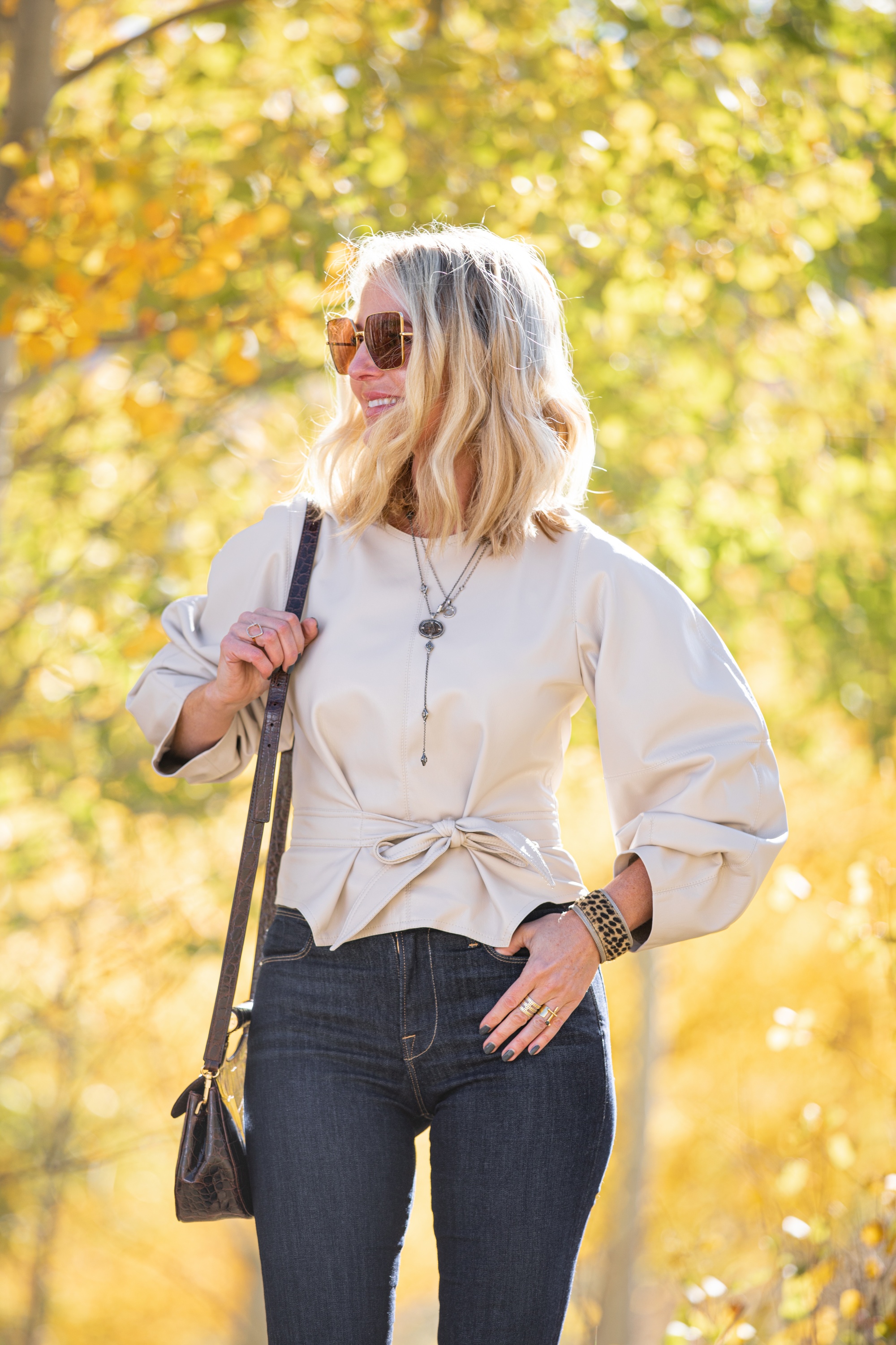 Fashion blogger wearing ivory Nanushka vegan leather tie front top, rag & bone skinny jeans, STUAD madeline croc embossed bag in Telluride, CO