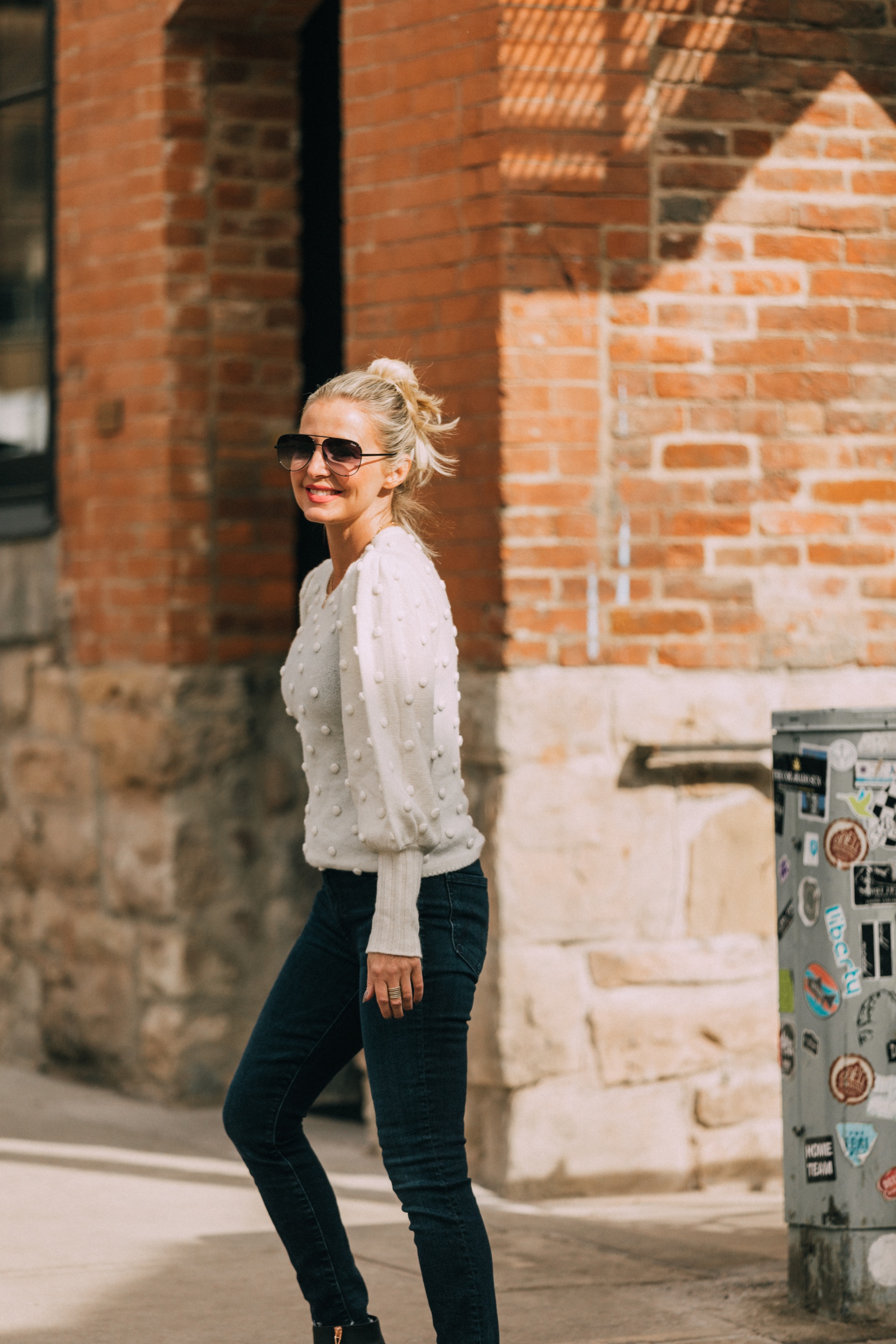 fashion blogger erin busbee wearing white balloon sleeve pom pom cashmere sweater dark wash skinny jeans paired with black cutout rose gold booties