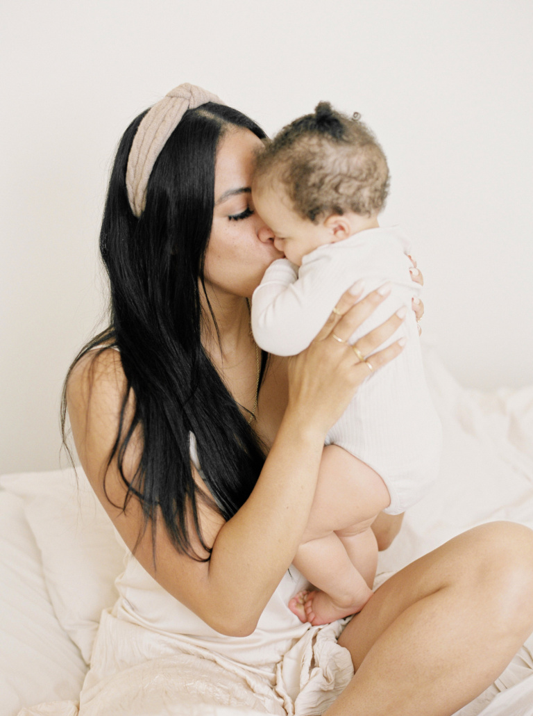 gifts new moms, multiracial young mom cuddling and kissing baby infant