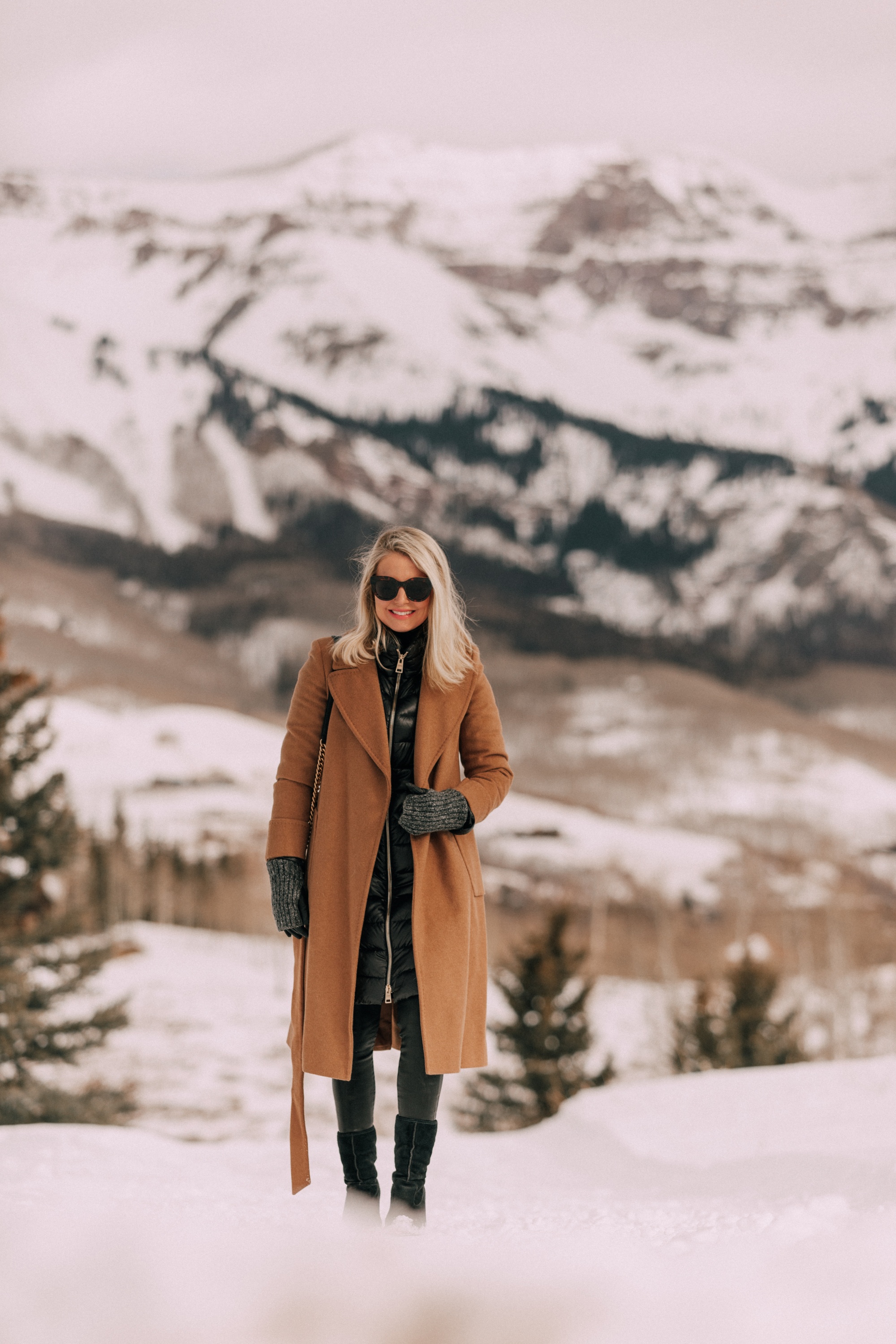 how to layer winter clothes to stay warm and look stylish, cold weather outfit black turtleneck sweater Citizens of Humanity Rocket leatherette skinny jeans, Ugg wedge boots, camel wool Mackage coat Mackage, and Herno puffer coat in Telluride, CO