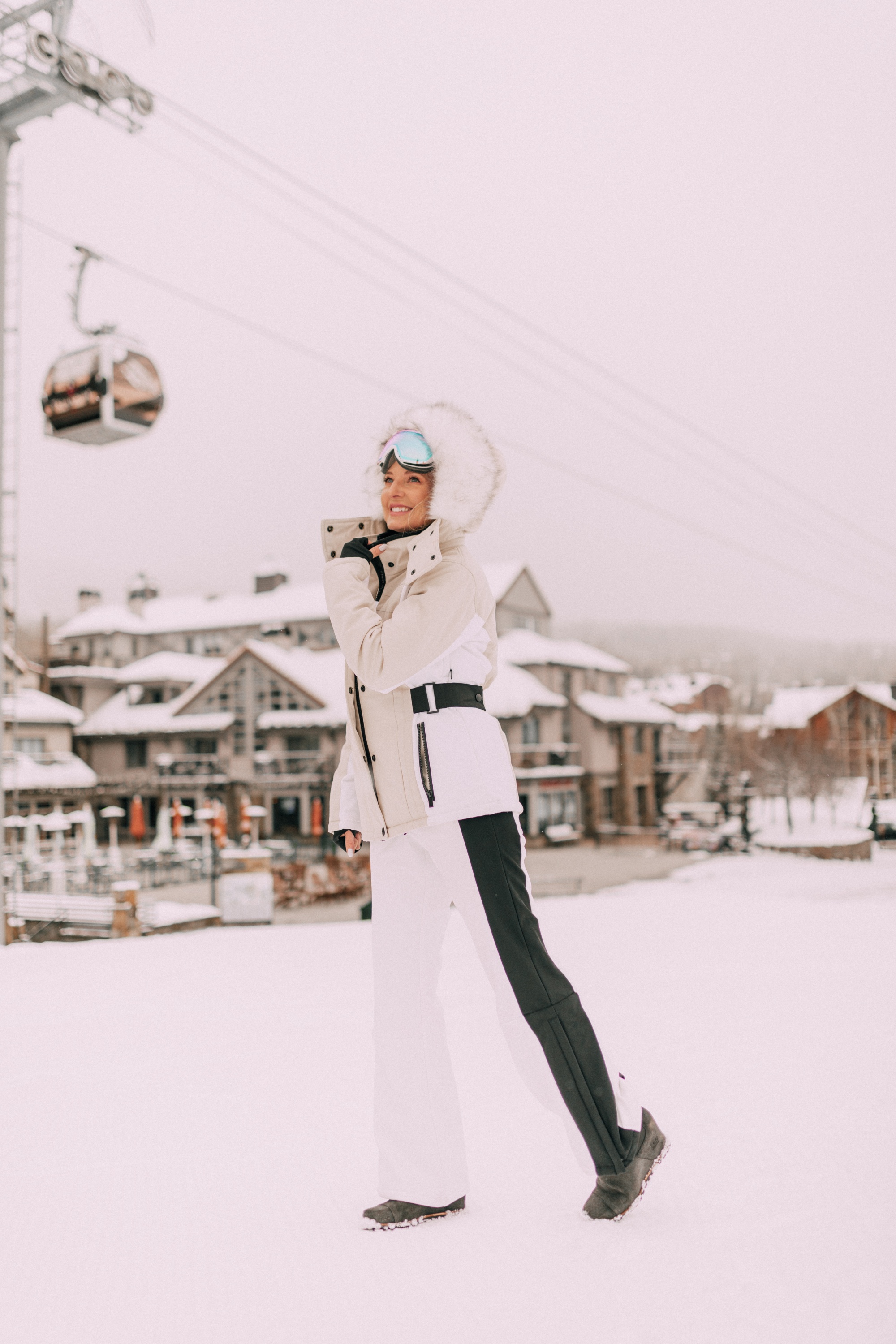 Chic Ski Gear, Fashion Blogger Over 40 Erin Busbee of BusbeeStyle.com wearing a tan and white coat, white striped ski pants, and peach color block bodysuit by Topshop SNO from Nordstrom in Telluride, Colorado
