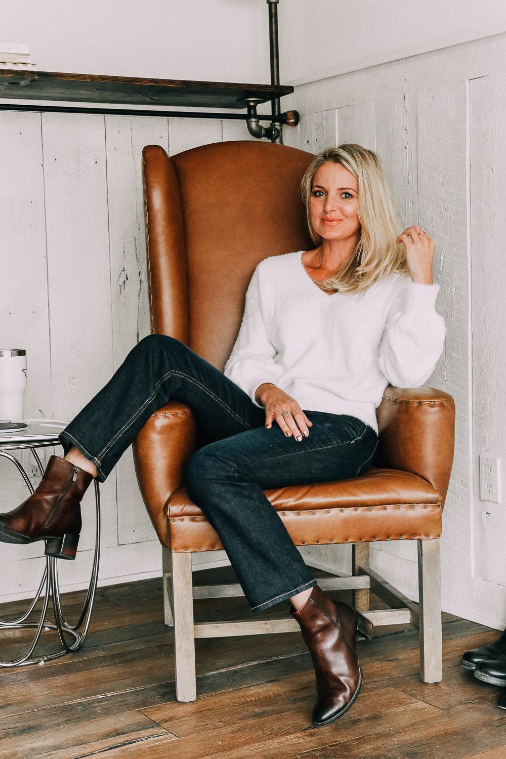 November Favorites, Fashion blogger Erin Busbee of BusbeeStyle.com wearing a white fuzzy v-neck sweater by Halogen with dark wash kick flare jeans and brown Ecco booties sitting in her studio in Telluride, CO