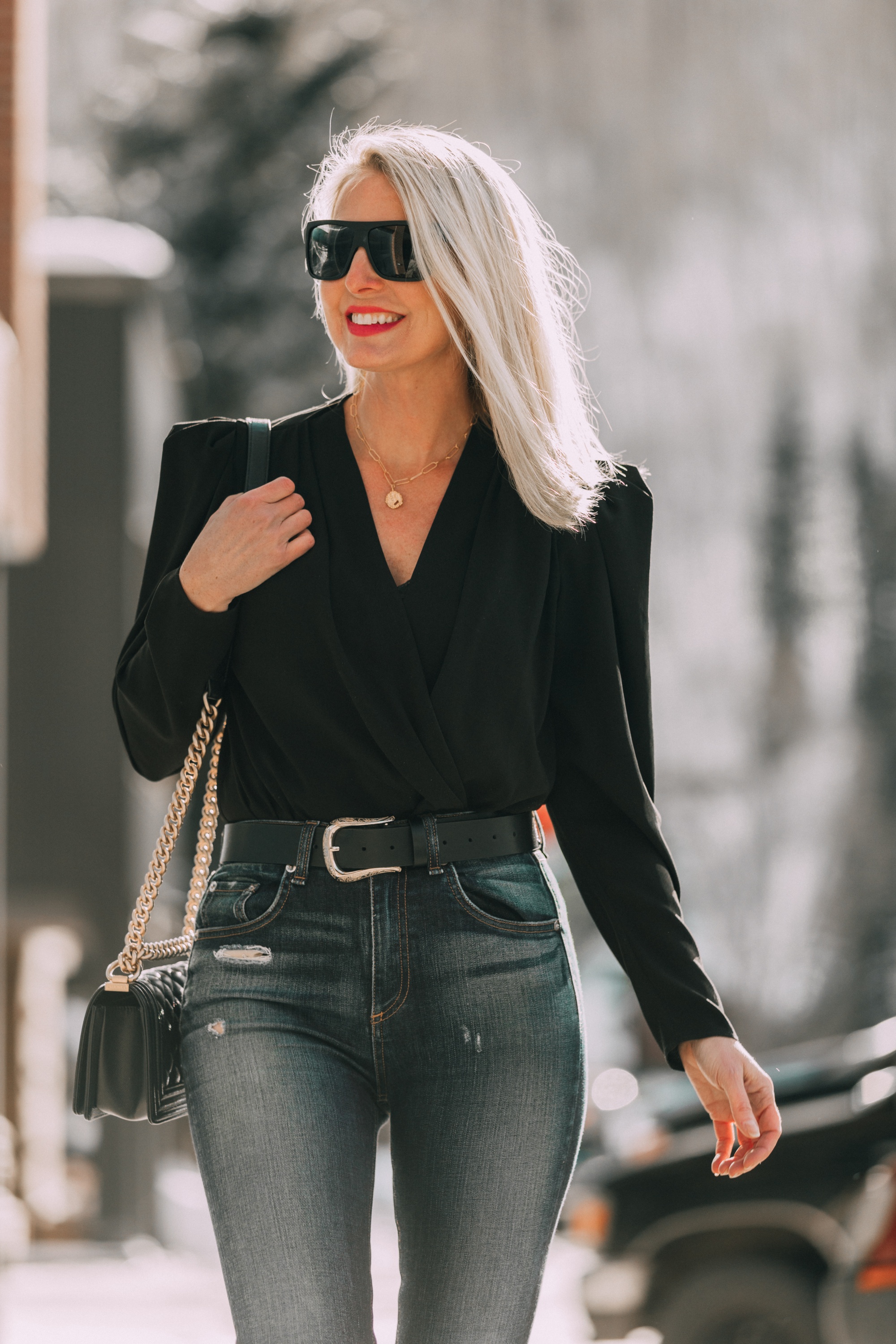 Date Night Outfits, Modebloggerin Erin Busbee von BusbeeStyle.com trägt eine schwarze Bluse mit Puffärmeln von IRO, zerrissene Röhrenjeans von Rag & Bone, schwarze kniehohe Stiefel mit Krokoprägung von Schutz, eine Chanel-Boy-Tasche und einen Topshop-Gürtel in Telluride, Colorado