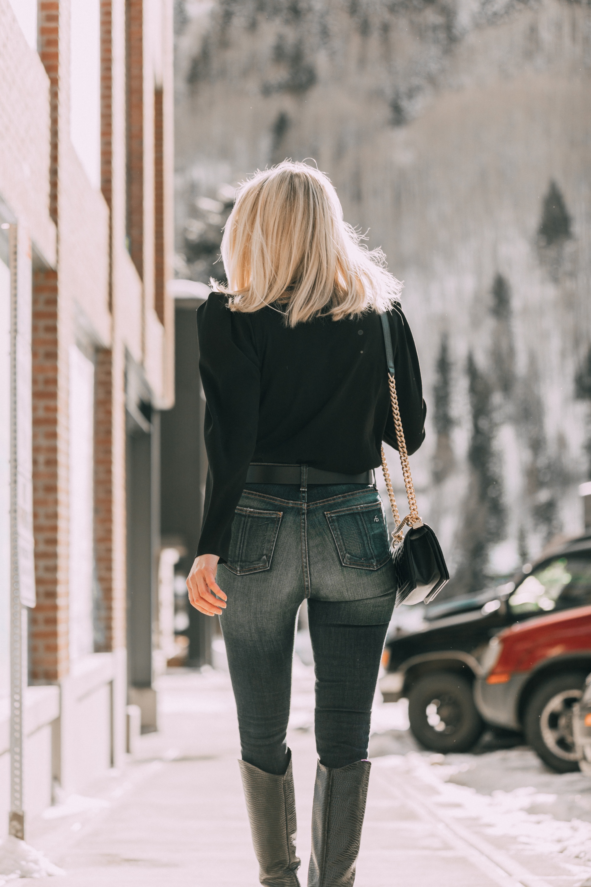 Date Night Outfits, Fashion blogger Erin Busbee of BusbeeStyle.com wearing a black puff sleeve blouse by IRO, ripped skinny jeans by Rag & Bone, Schutz black croc-embossed knee high boots, Chanel boy bag, and Topshop belt in Telluride, Colorado