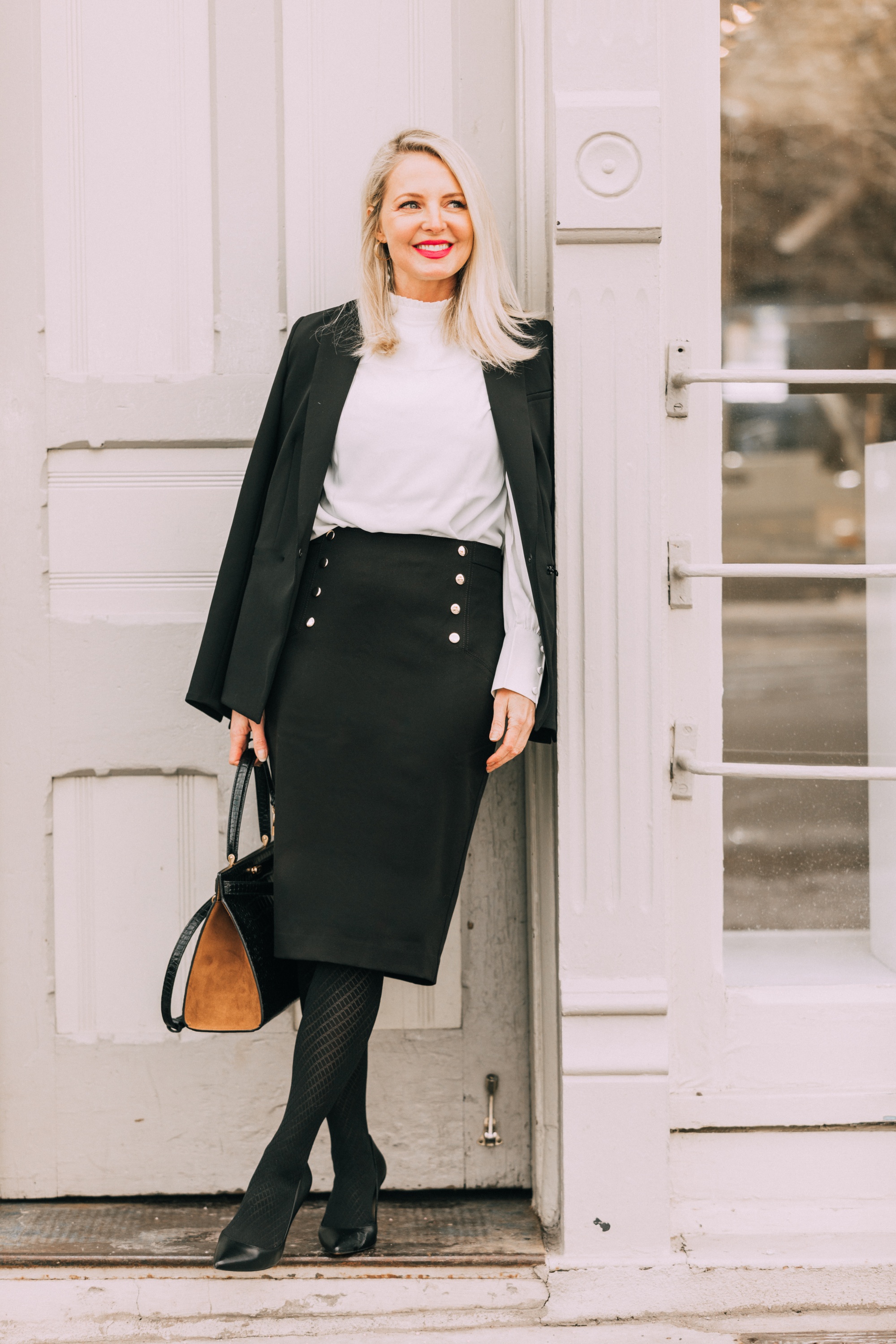 Wardrobe Basics, Fashion blogger Erin Busbee of BusbeeStyle.com sharing wardrobe basics from Ann Taylor wearing a black pencil skirt with sailir buttons, a white ruffle neck blouse, classic black blazer, black tights, and black pumps all from Ann Taylor in Telluride, Colorado
