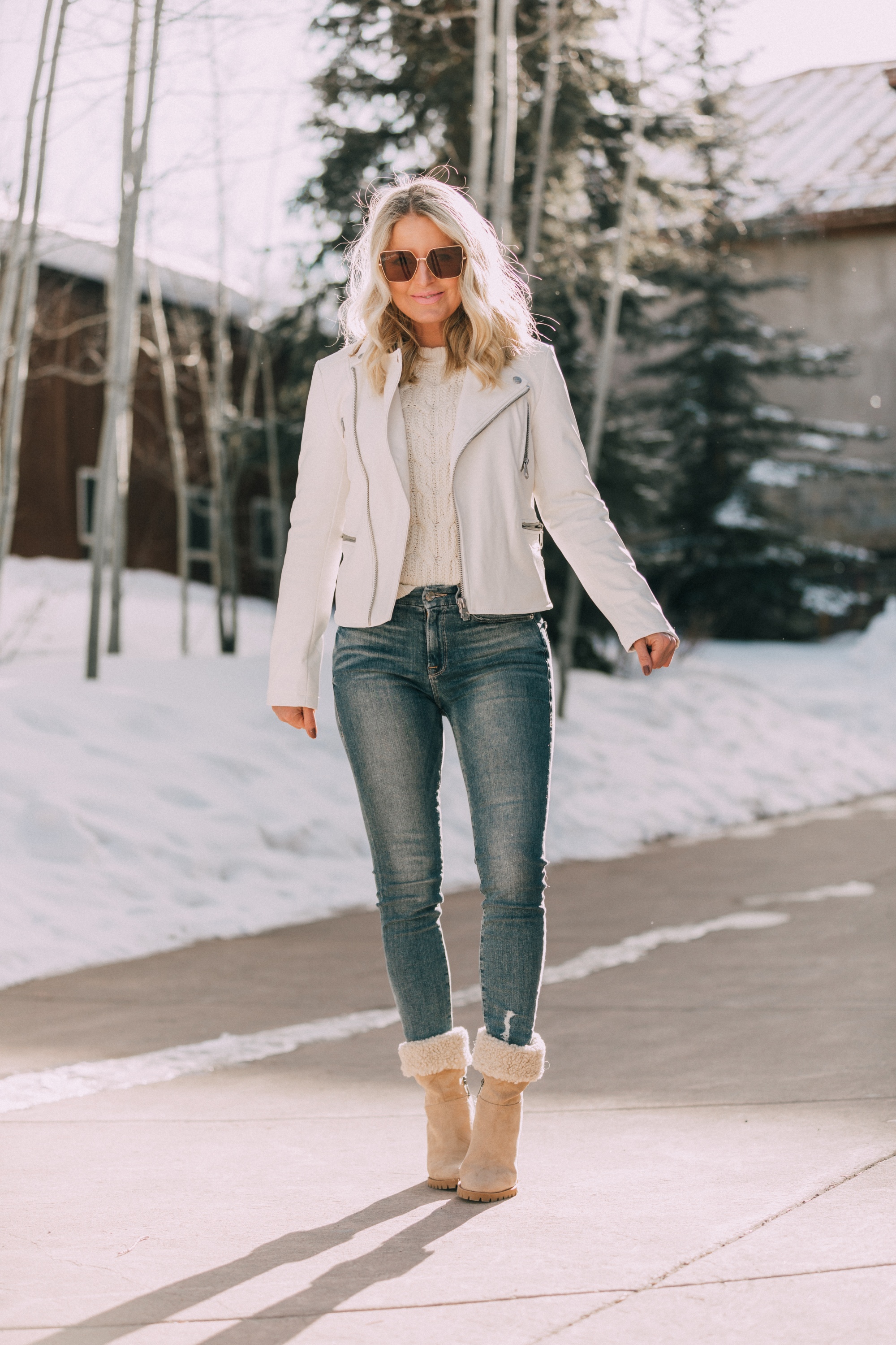 walmart scoop fashion blogger wearing white faux leather moto jacket, white cable knit sweater and medium wash skinny jeans and foldover shearling tan heeled womens booties in Telluride, Colorado