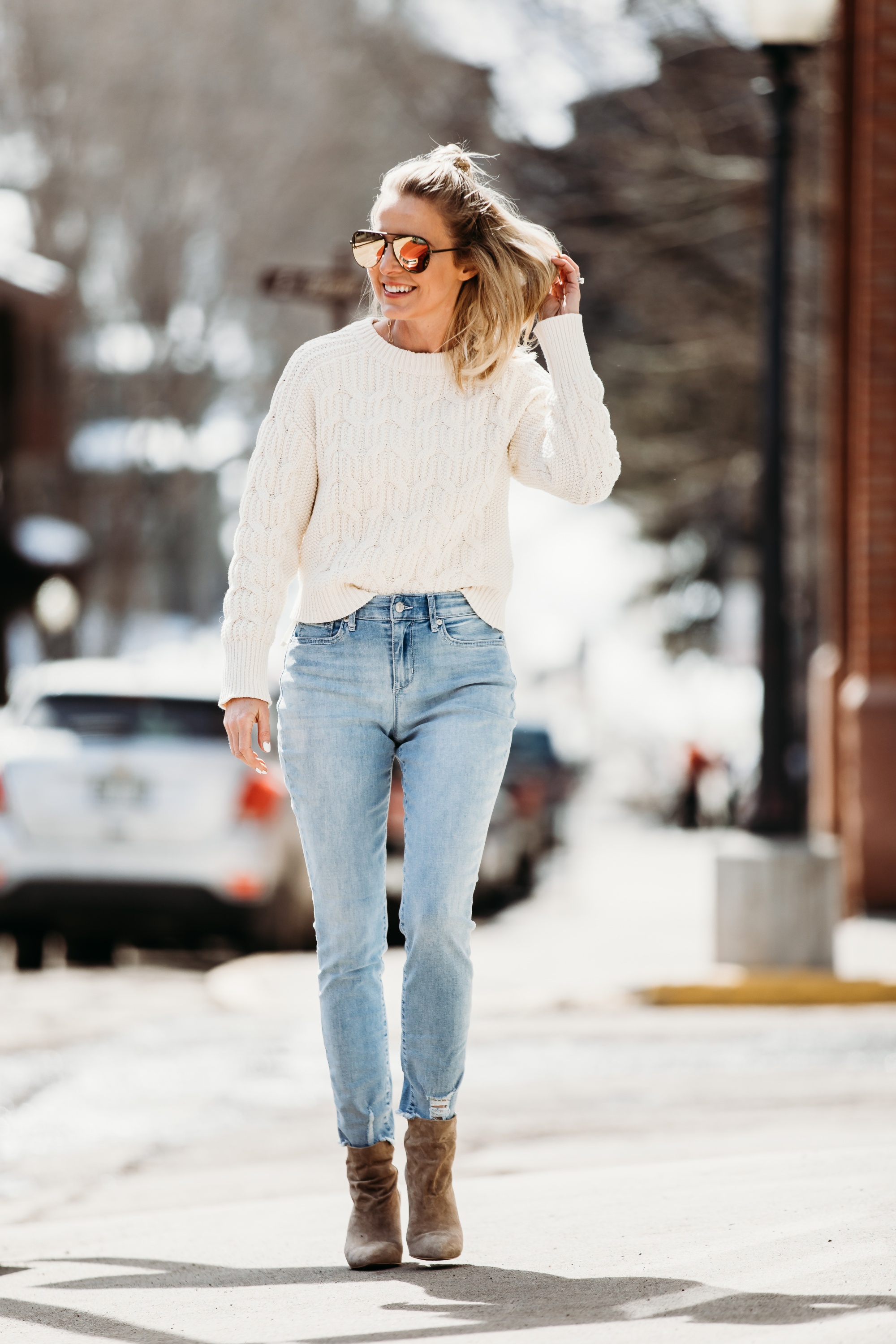 White Sweaters, Fashion blogger Erin Busbee of BusbeeStyle.com wearing a white cable knit sweater by Scoop, light wash skinny jeans by Sofia Vergara, brown suede booties, and green mirrored QUAY sunglasses from Walmart walking in Telluride, Colorado