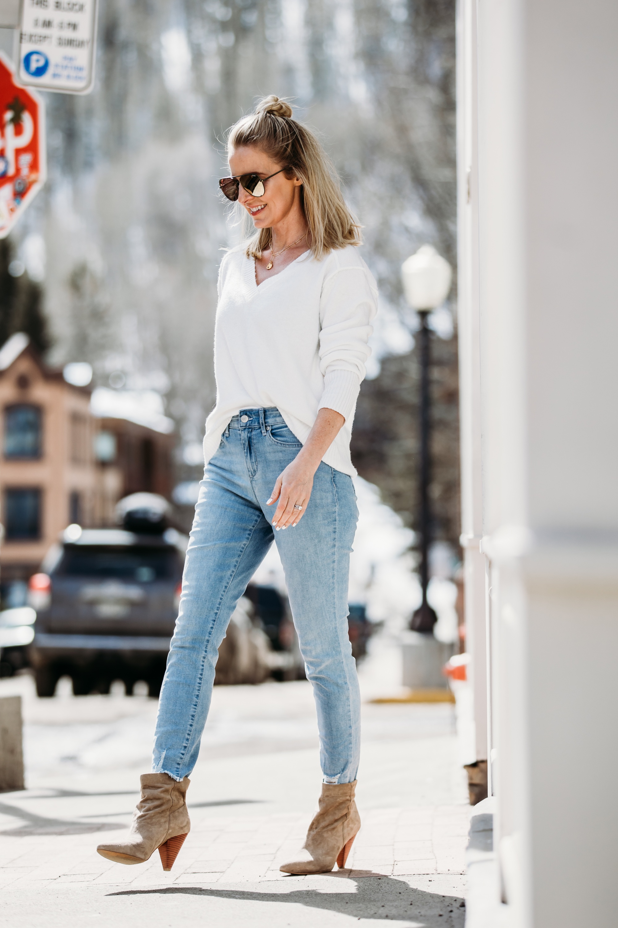 White Sweaters, Fashion blogger Erin Busbee of BusbeeStyle.com wearing a white v-neck sweater by Scoop, light wash skinny jeans by Sofia Vergara, brown suede booties, and green mirrored QUAY sunglasses from Walmart walking in Telluride, Colorado