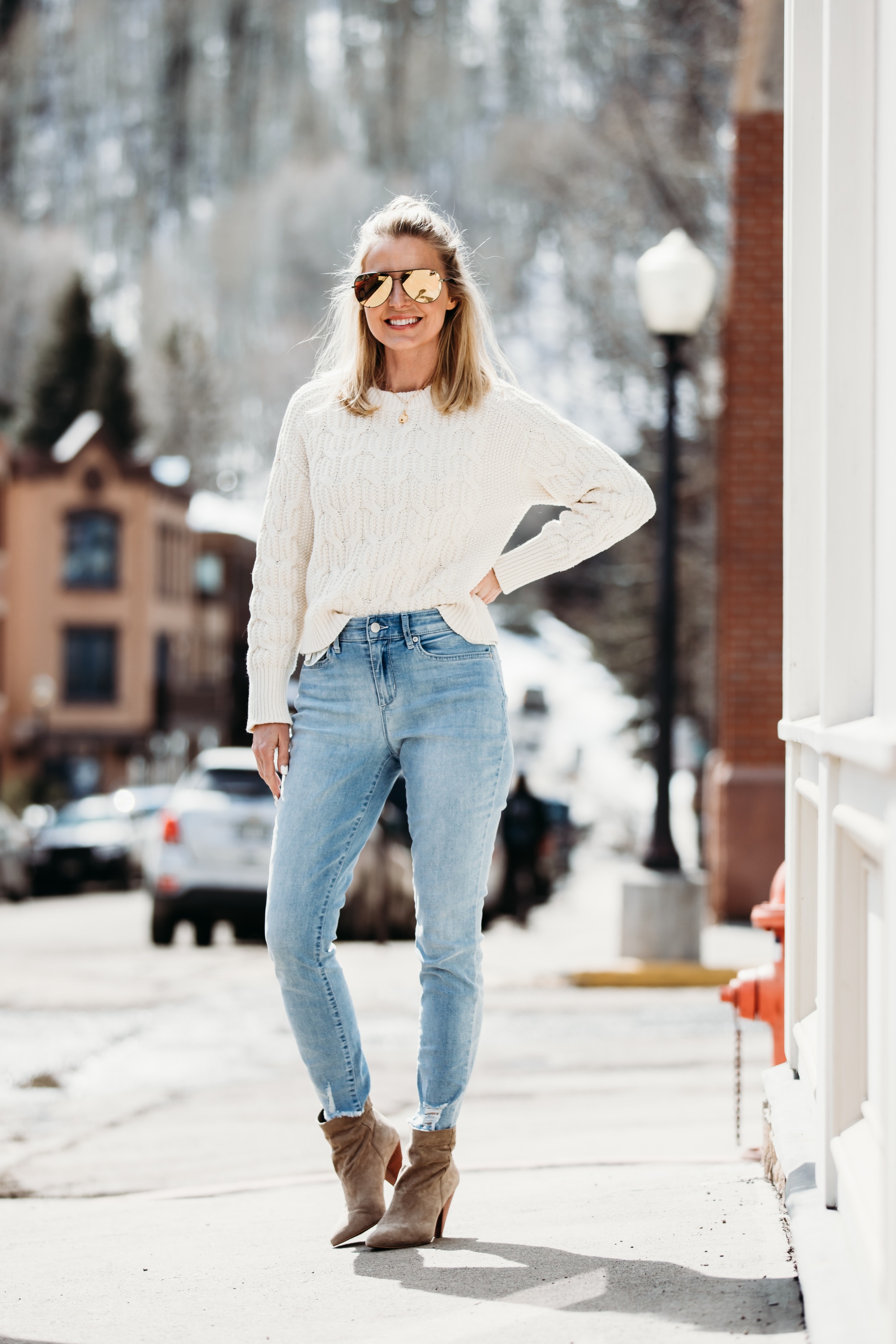 White Sweaters, Fashion blogger Erin Busbee of BusbeeStyle.com wearing a white cable knit sweater by Scoop, light wash skinny jeans by Sofia Vergara, brown suede booties, and green mirrored QUAY sunglasses from Walmart in Telluride, Colorado