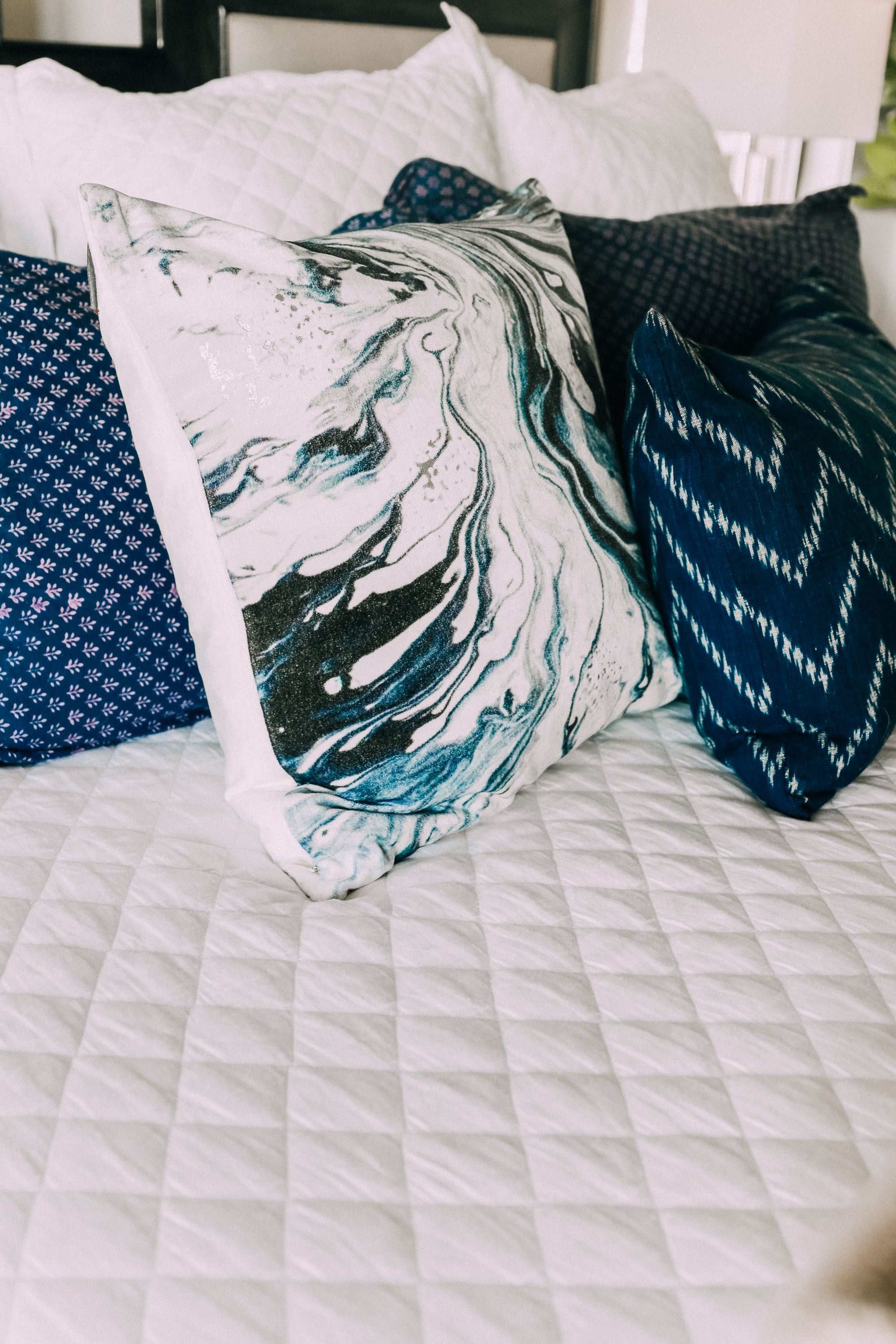 master bedroom blue and white throw pillows on white bedspread