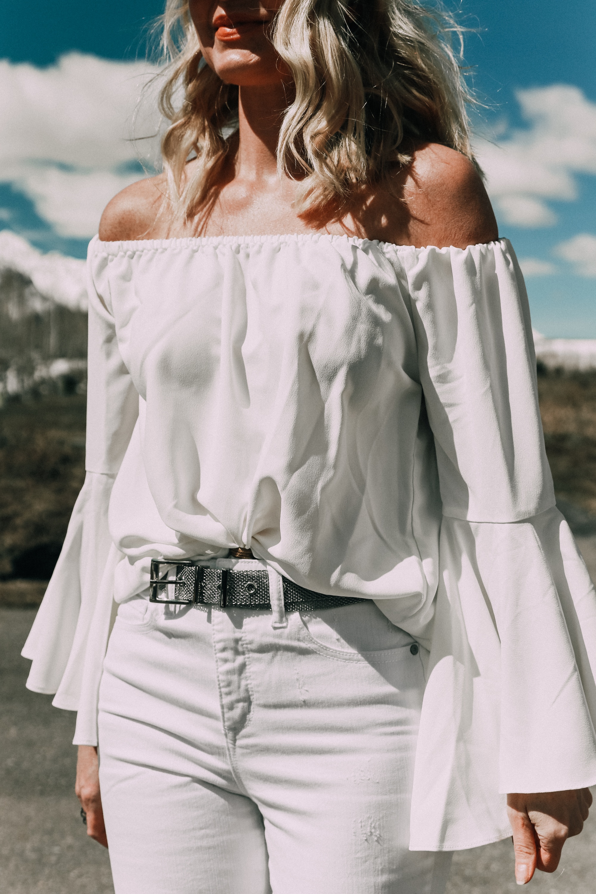 Spring style staples, fashion blogger Erin Busbee of BusbeeStyle.com wearing a white bell sleeve off the shoulder blouse with white kick flare jeans by Scoop from Walmart in Telluride, CO