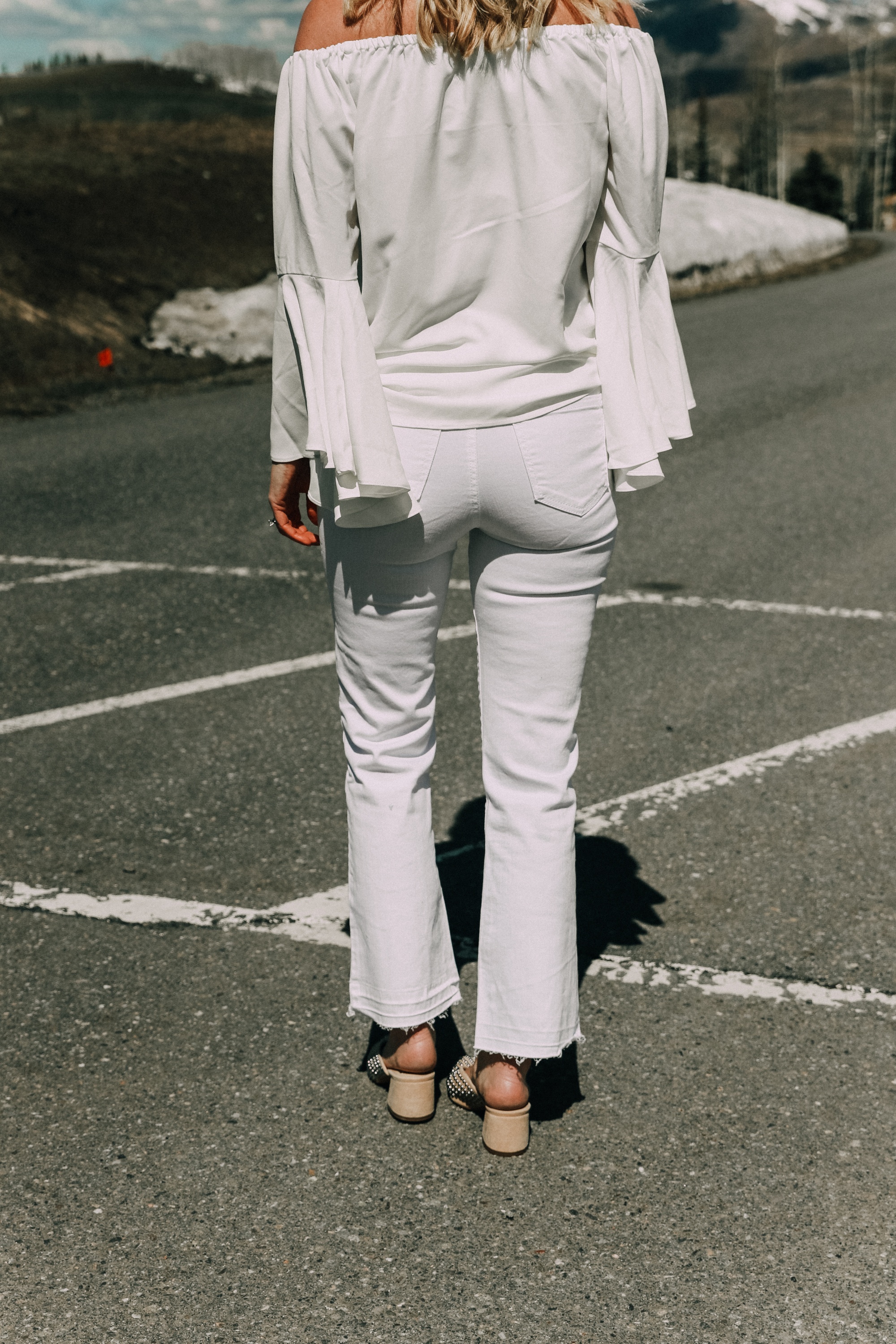 Spring style staples, fashion blogger Erin Busbee of BusbeeStyle.com wearing a white bell sleeve off the shoulder blouse with white kick flare jeans by Scoop from Walmart in Telluride, CO