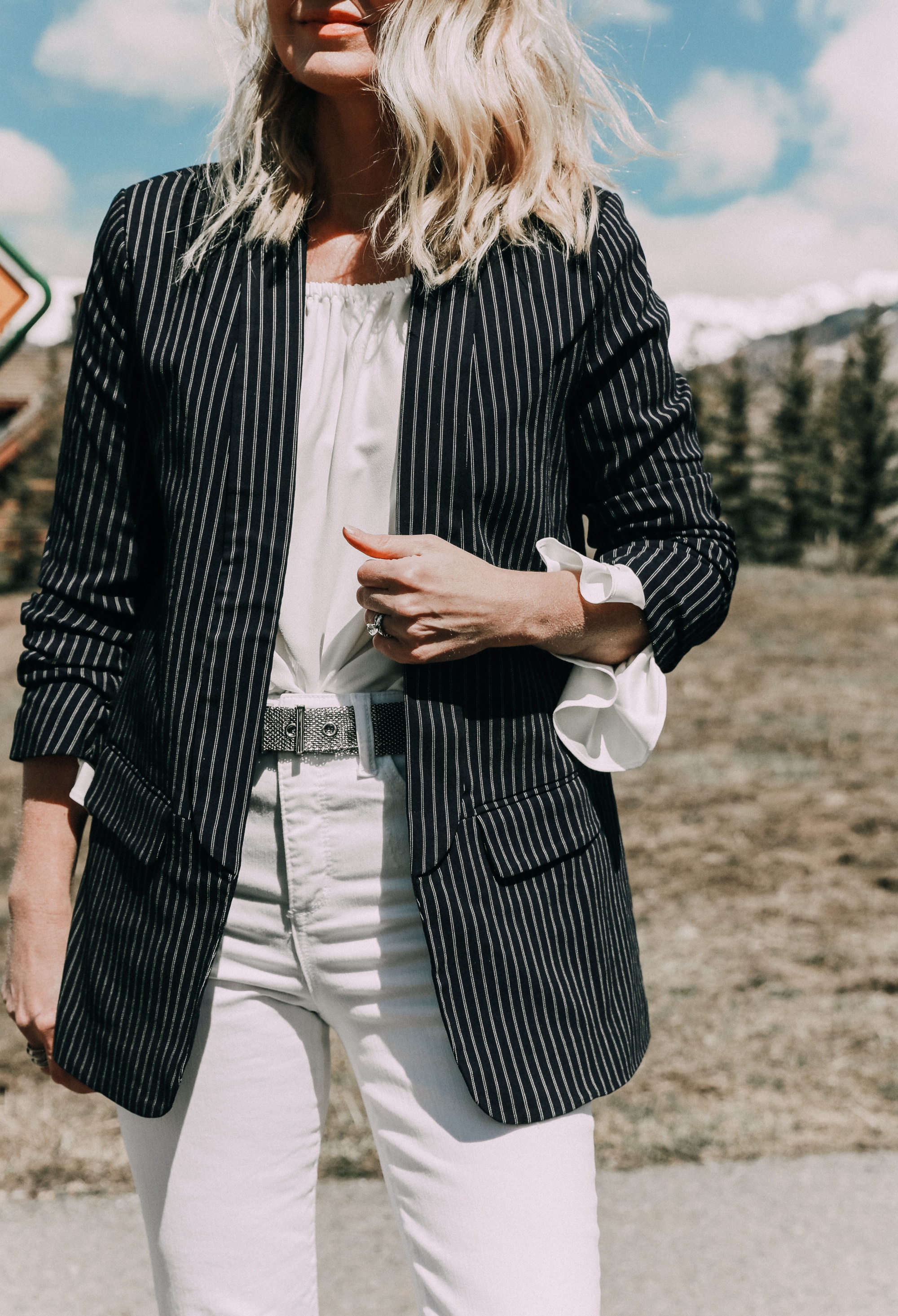 Spring style staples, fashion blogger Erin Busbee of BusbeeStyle.com wearing a white bell sleeve off the shoulder blouse under a navy pinstripe balzer with white kick flare jeans and white pumps by Scoop from Walmart in Telluride, CO