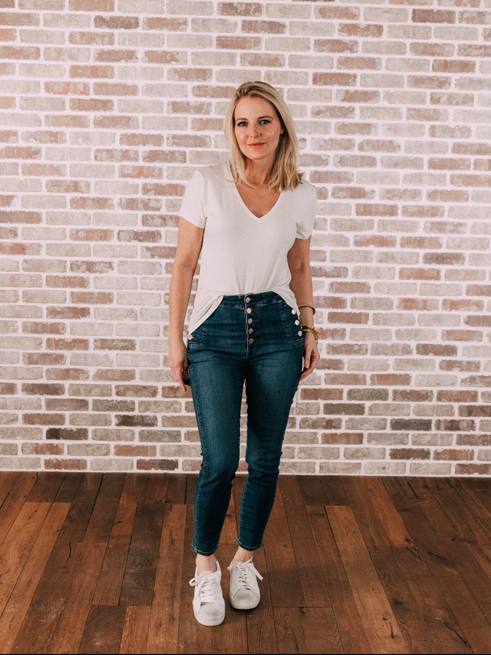 Best White Tees, Fashion blogger Erin Busbee of BusbeeStyle.com sharing wear a white tee by Michael Stars with button fly skinny jeans and white sneakers in her studio in Telluride, Colorado