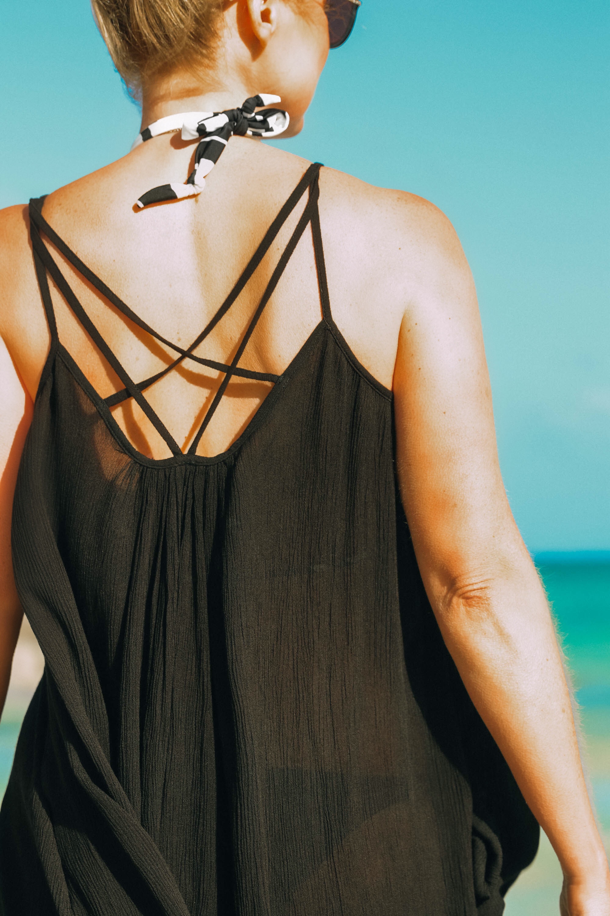 Best Coverups, Fashion blogger Erin Busbee of BusbeeStyle.com wearing a black strappy Elan coverup dress over a Vix swimsuit holding studded Vince Camuto sandals in the Bahamas