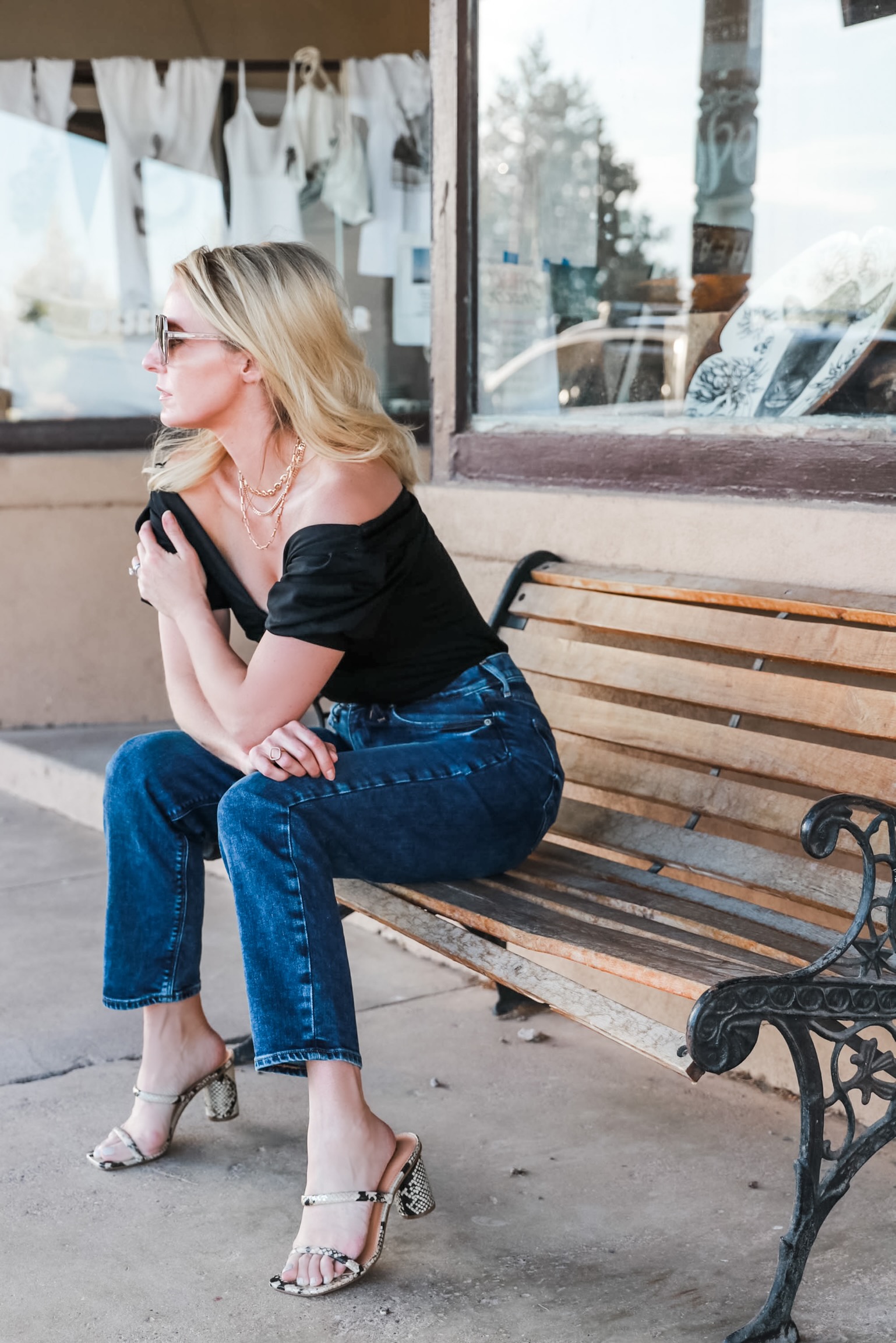 fashion blogger sitting outside Gage Hotel Texas wearing Express super high waisted dark wash mom jeans with python heeled sandals