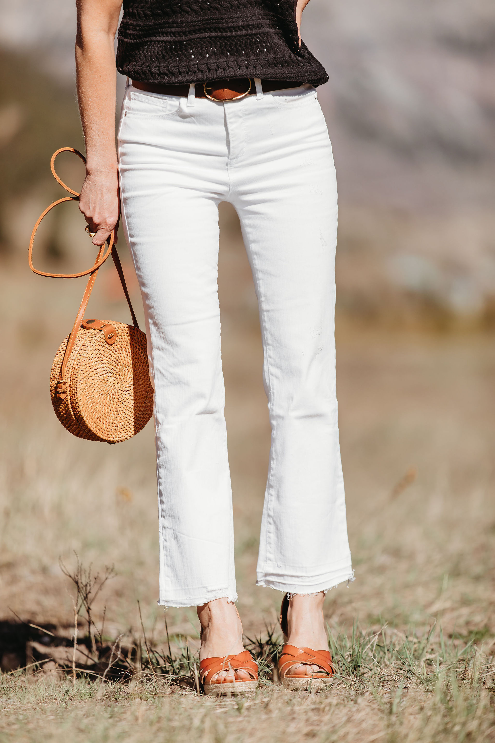 Affordable Summer Tops, Fashion blogger Erin Busbee of BusbeeStyle.com wearing a black crocheted flutter sleeve top with white cropped kick flare jeans, straw circle bag, and brown espadrille wedges by Scoop from Walmart in Telluride, Colorado