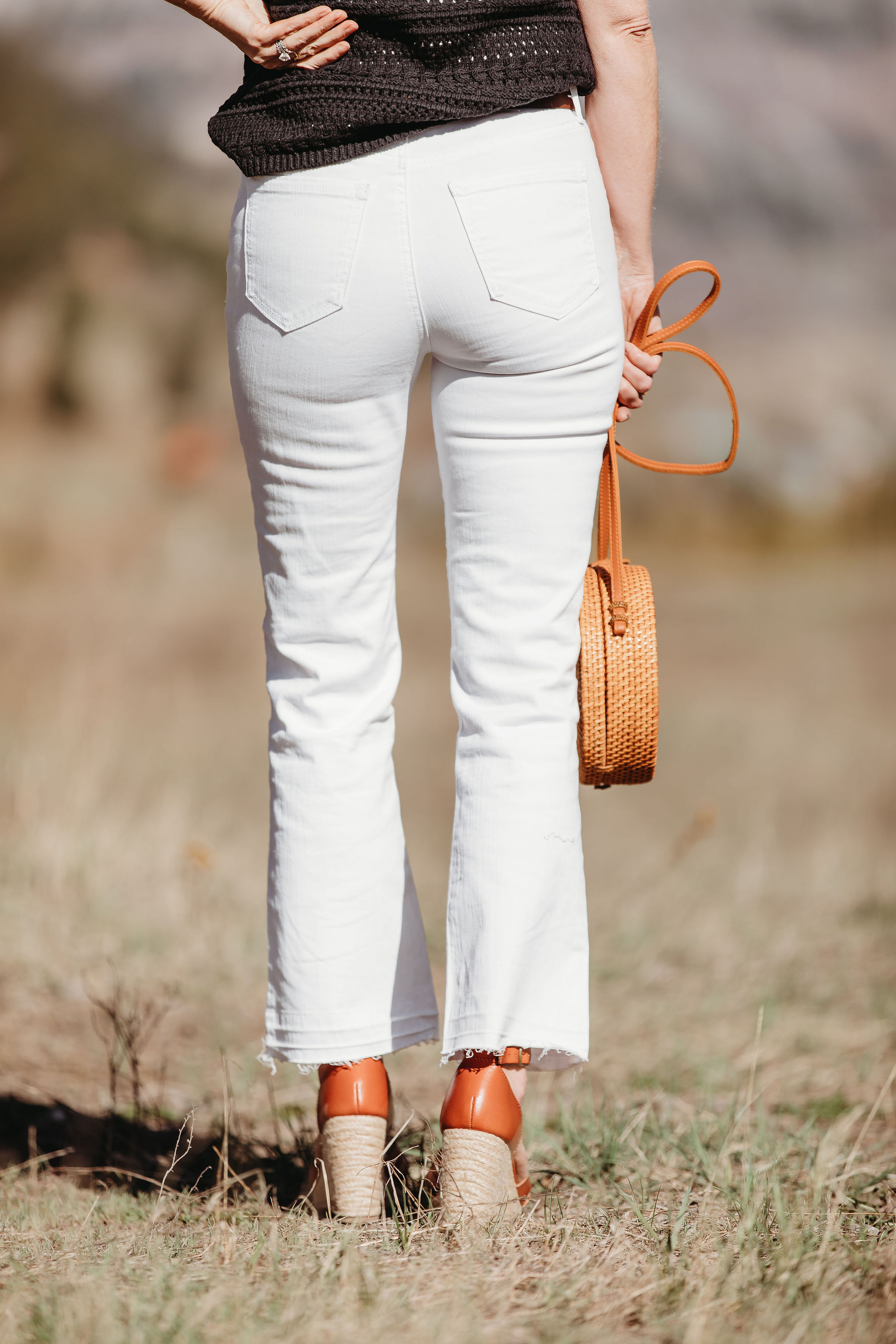 Affordable Summer Tops, Fashion blogger Erin Busbee of BusbeeStyle.com wearing a black crocheted flutter sleeve top with white cropped kick flare jeans, straw circle bag, and brown espadrille wedges by Scoop from Walmart in Telluride, Colorado