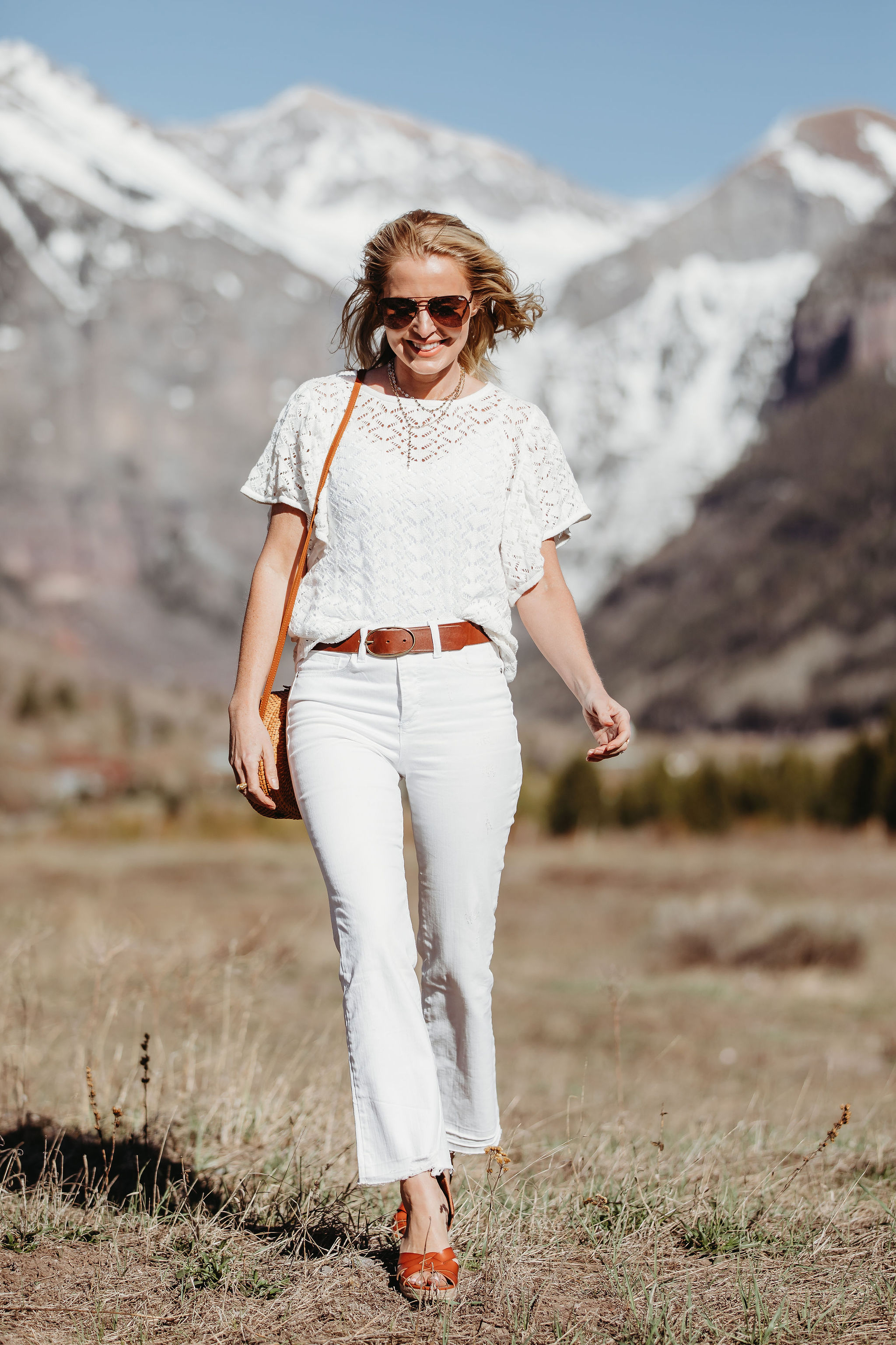 Affordable Summer Tops, Fashion blogger Erin Busbee of BusbeeStyle.com wearing a white knit top with white cropped kick flare jeans, straw circle bag, and brown espadrille wedges by Scoop from Walmart in Telluride, Colorado