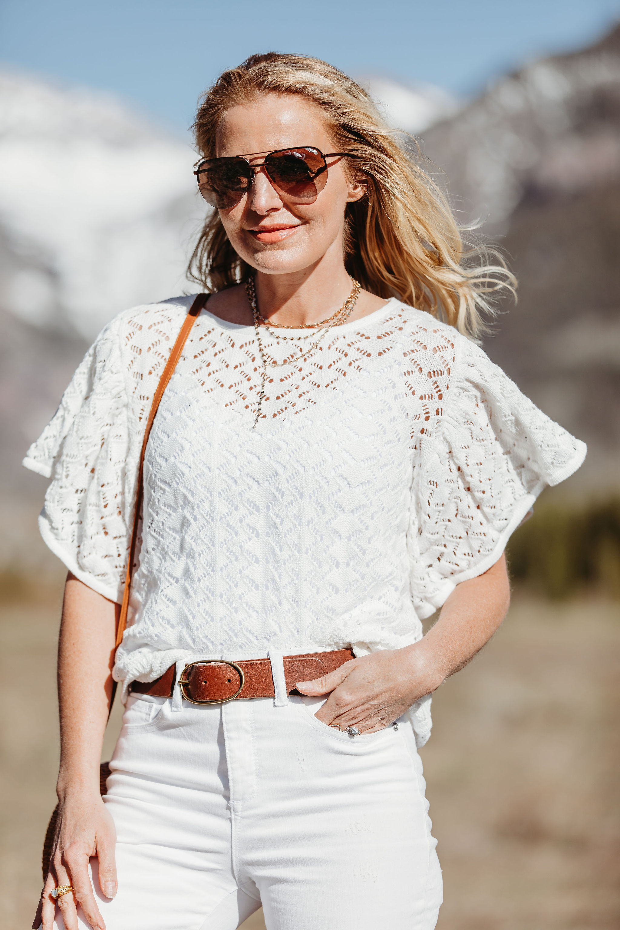 Affordable Summer Tops, Fashion blogger Erin Busbee of BusbeeStyle.com wearing a white knit top with white cropped kick flare jeans, straw circle bag, and brown espadrille wedges by Scoop from Walmart in Telluride, Colorado