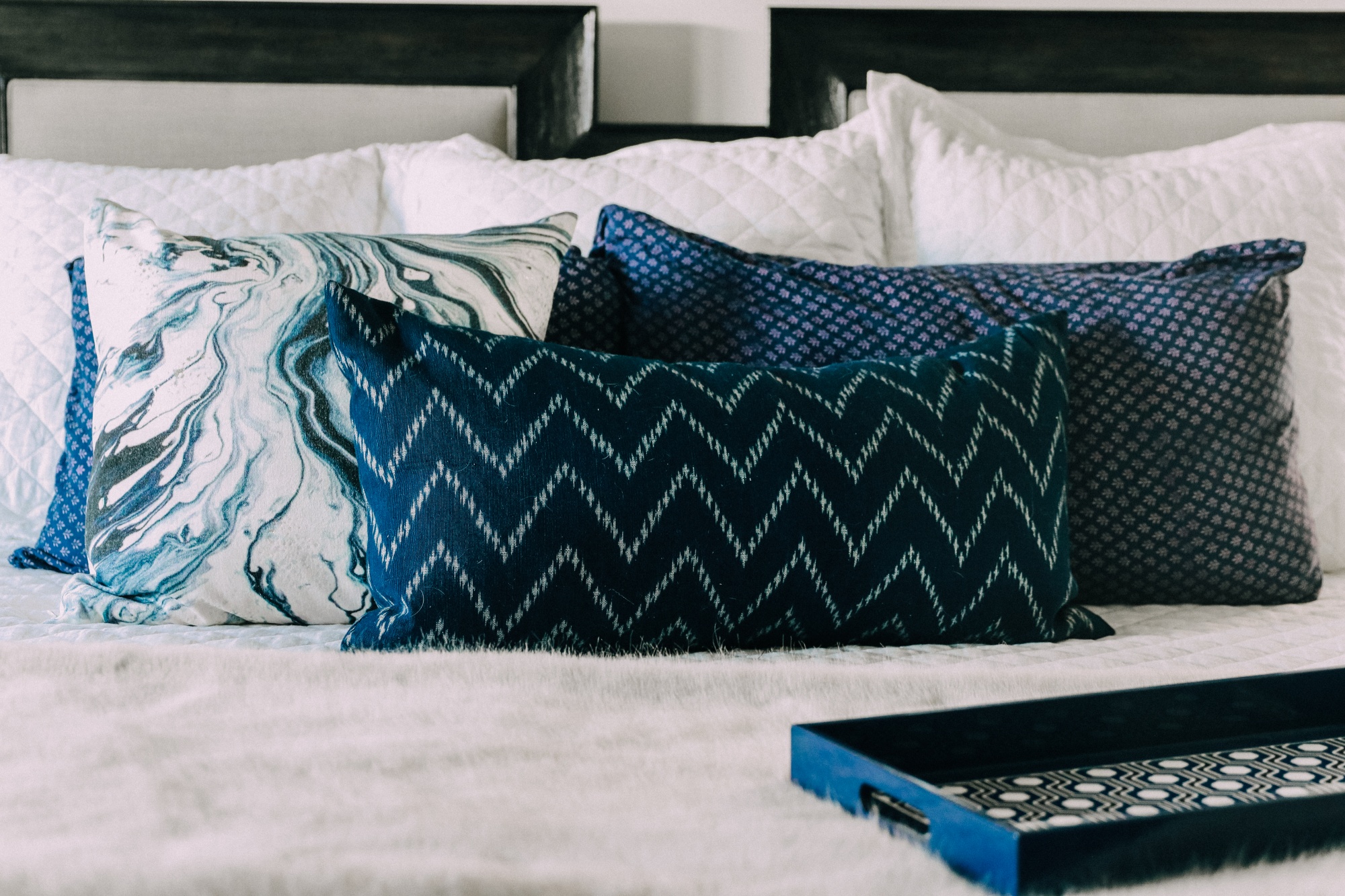 blue navy and white throw pillows arranged styled on top of king bed, how many throw pillows should you have on your bed