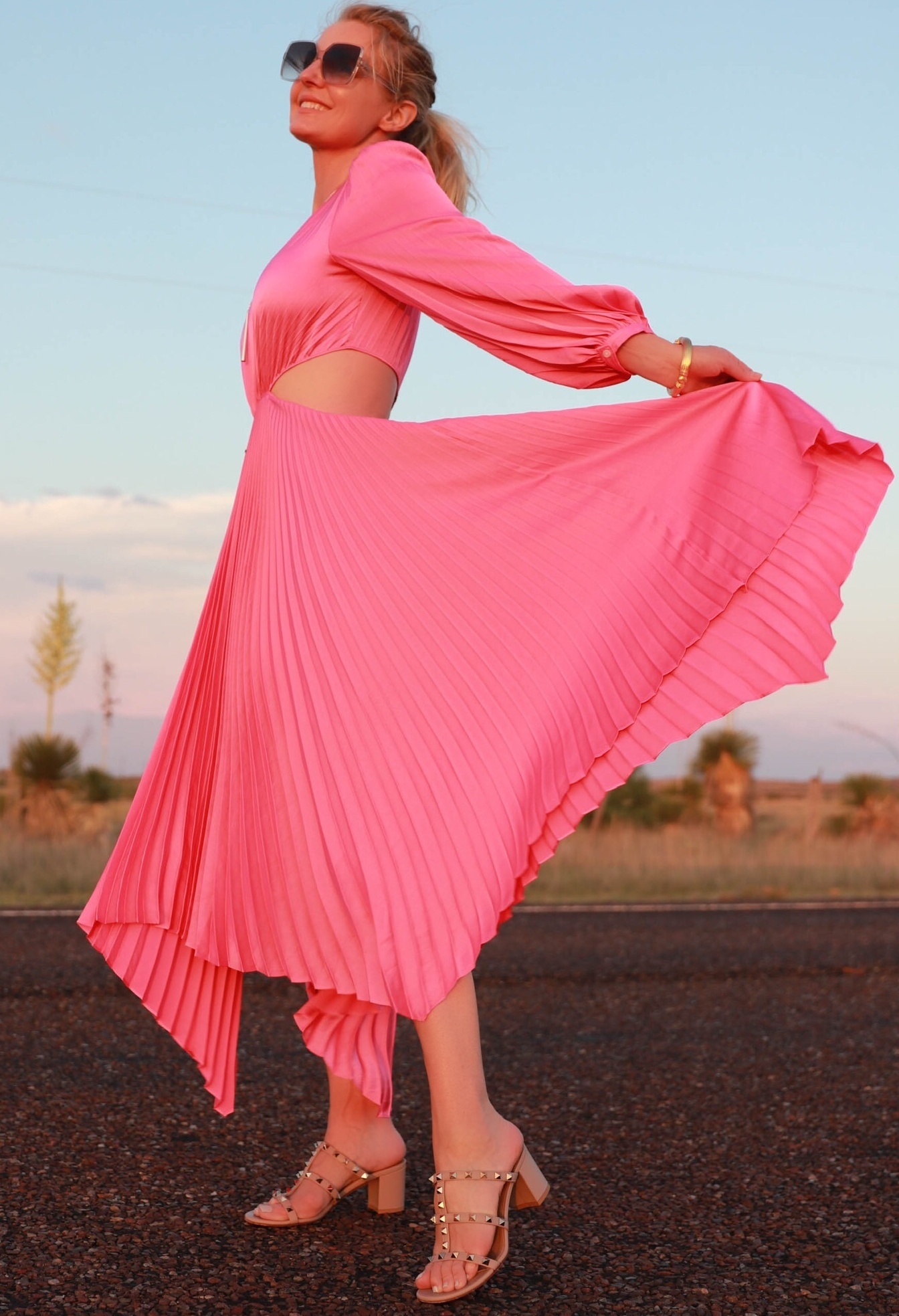 Pink Fashion Finds, Fashion blogger Erin Busbee of Busbee Style wearing a pink pleated dress by A.L.C. with Valentino Rockstud sandals walking in the road in South Texas