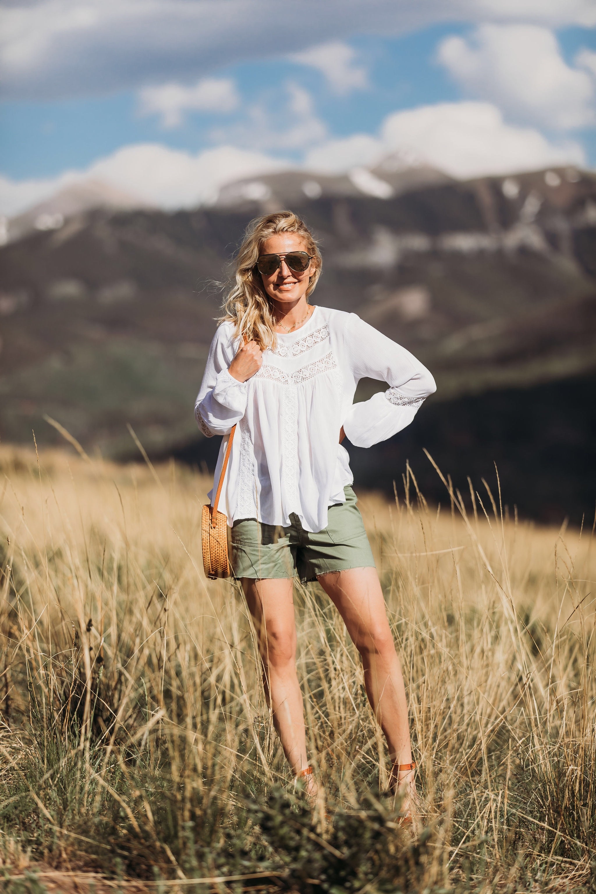 Ways To Wear Shorts Over 40, Fashion blogger Erin Busbee of BusbeeStyle.com wearing a white long sleeve top, green cargo shorts, and brown espadrille wedges by Scoop and a brown woven bag and QUAY sunglasses from Walmart in Telluride, Colorado