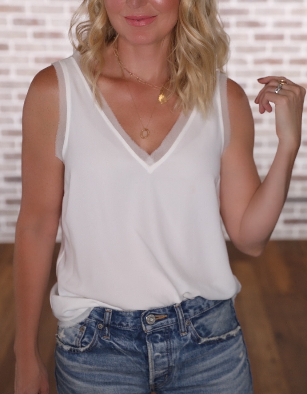July Best Sellers, Fashion blogger Erin Busbee of Busbee Style wearing a white Chelsea28 raw edge tank with moussy vintage jeans in her studio in Telluride, Colorado
