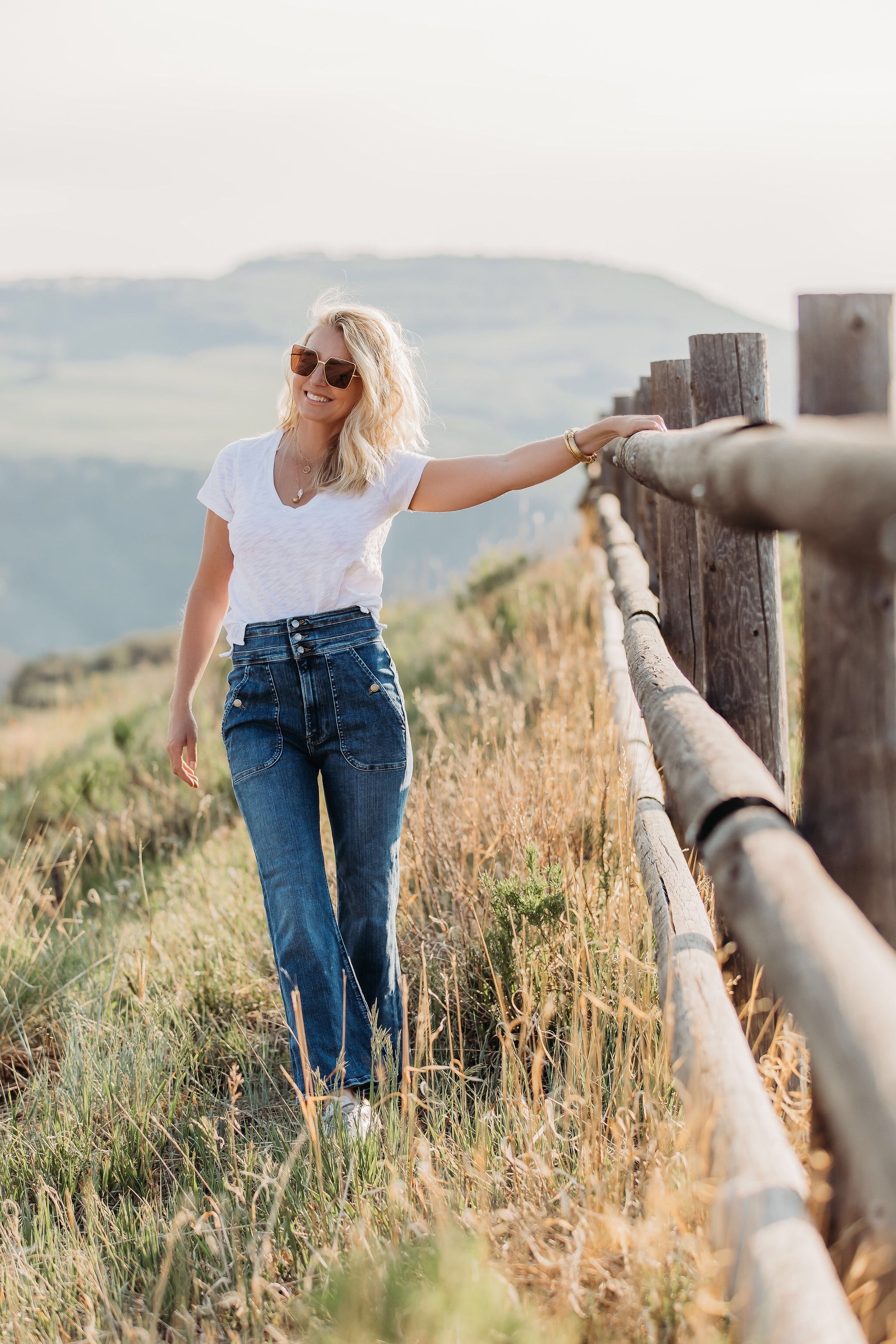 Summer Mom Style, Fashion blogger Erin Busbee of Busbee Style wearing a white v-neck tee with wide leg flare jeans by Frame, Golden Goose sneakers, Julie Vos bracelets, Aligheri necklaces, and Saint Laurent sunglasses in Telluride, Colorado