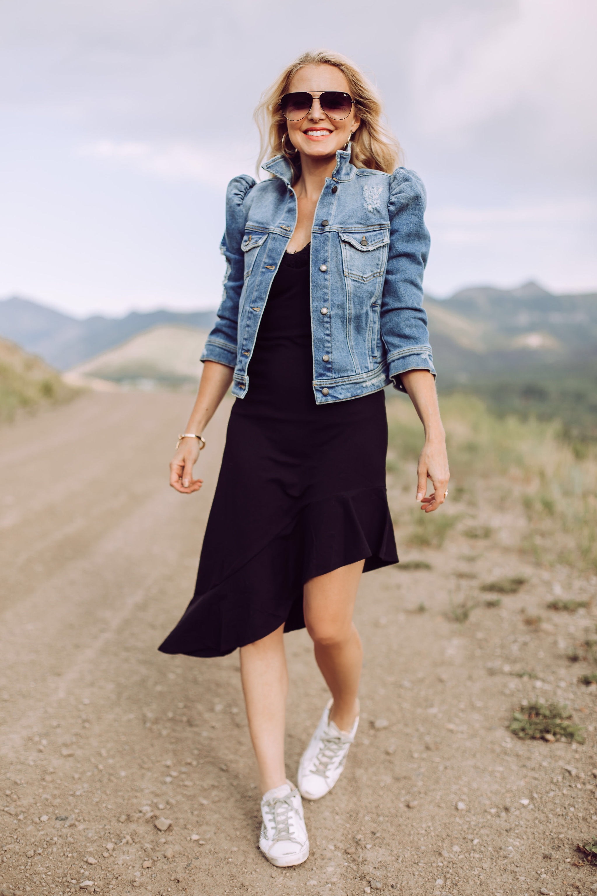 Day To Date Night Outfits, Fashion blogger Erin Busbee of Busbee Style wearing a black susana monaco dress with golden goose sneakers, retrofete denim puff sleeve jacket and aviator sunglasses in Telluride, Colorado