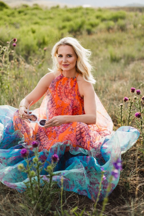 How To Manifest Anything, Modebloggerin Erin Busbee von Busbee Style, trägt ein orange-blaues Kleid von Staud Ina und eine weiße Sonnenbrille und läuft in Telluride, Colorado umher