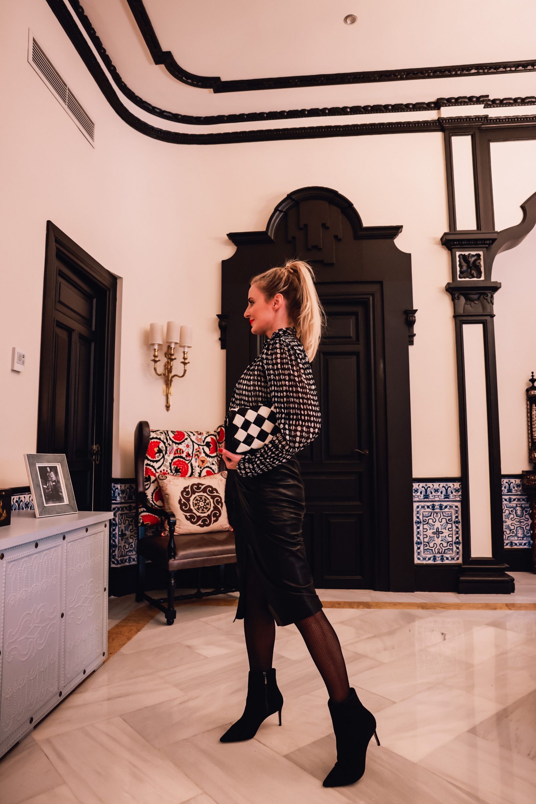office outfits, stylish office outfits, chic office outfits, office outfits over 40, workwear over 40, stylish workwear, erin busbee, iro black leather midi skirt, ba&sh printed blouse pointed toe schutz boots, ba&sh black and white checkered bag, sevilla, spain, office to date night outfit