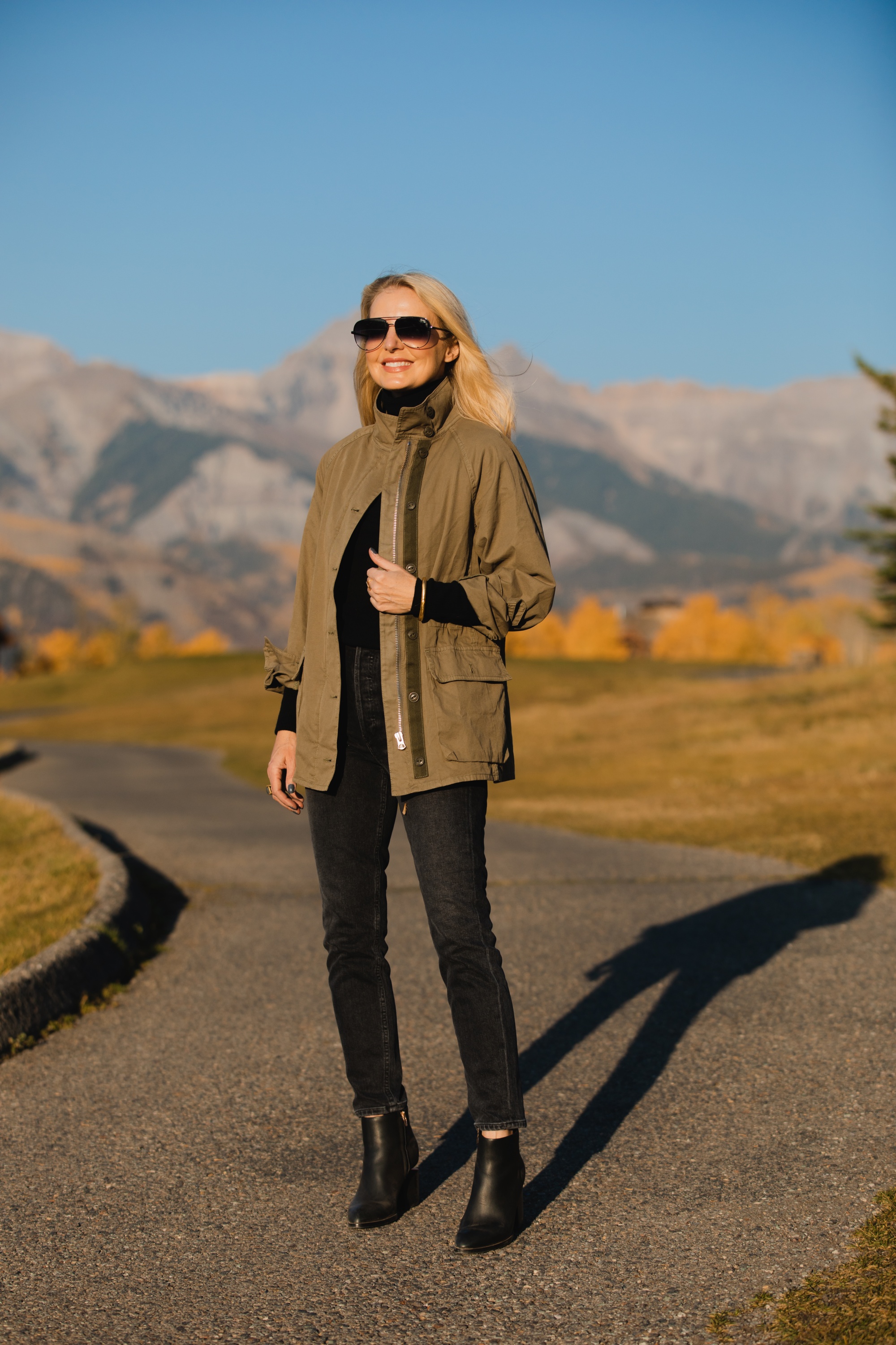 How To Wear A Cargo Jacket, Erin Busbee of Busbee Style wearing a green cargo jacket by rag & bone, black turtleneck puff sleeve cashmere sweater by Aqua, gray wash Nico slim fit jeans by Agolde, QUAY sunglasses, and Alexander Wang cutout booties in Telluride, Colorado