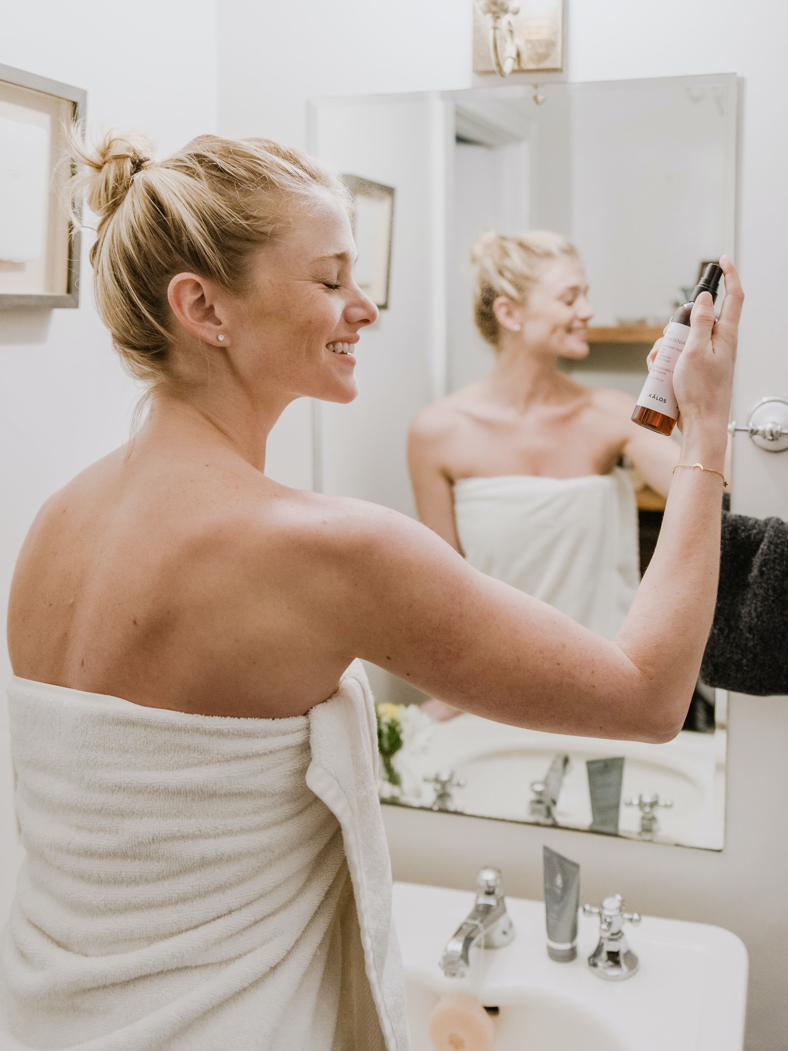 Spend time on yourself first, Blonde woman with hair in bun in bathroom spraying face with beauty product taking time for self care, start saying no