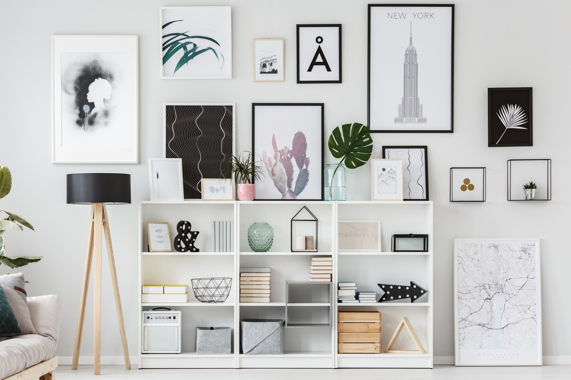 5 Easy Steps To The Perfect and Unique Gallery Wall with a black and white and floral theme showing pieces leaning up against shelves and propped on the floor for a full ceiling to floor look which includes white shelving
