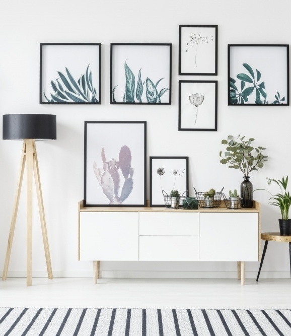 5 Easy Steps To The Perfect and Unique Gallery Wall with botanical posters and perfect spacing between framed artwork against an all white wall and a console below providing a great layout example