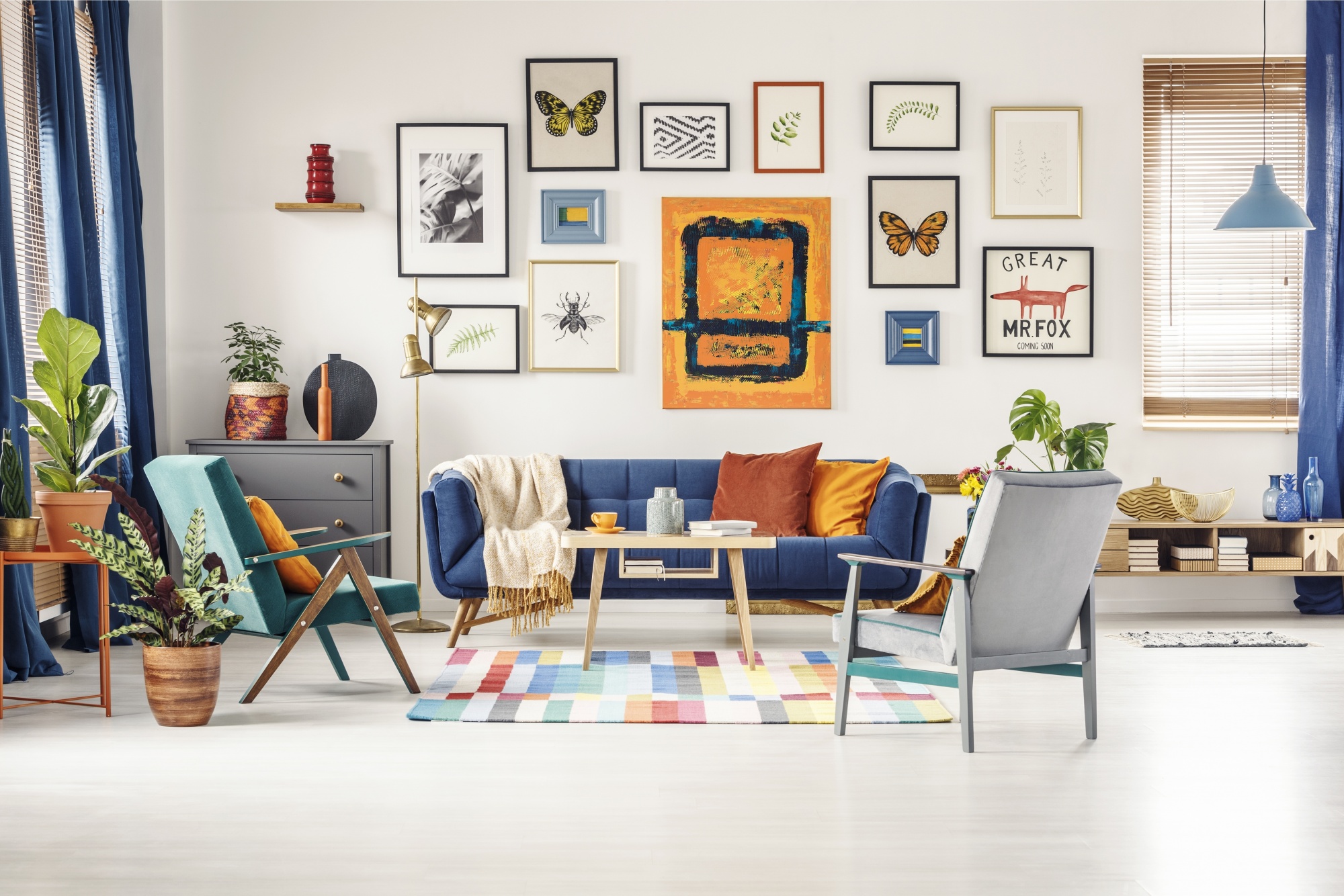 5 Easy Steps To The Perfect and Unique Gallery Wall above a blue couch with multiple artistic images and butterflies framed against an all white wall