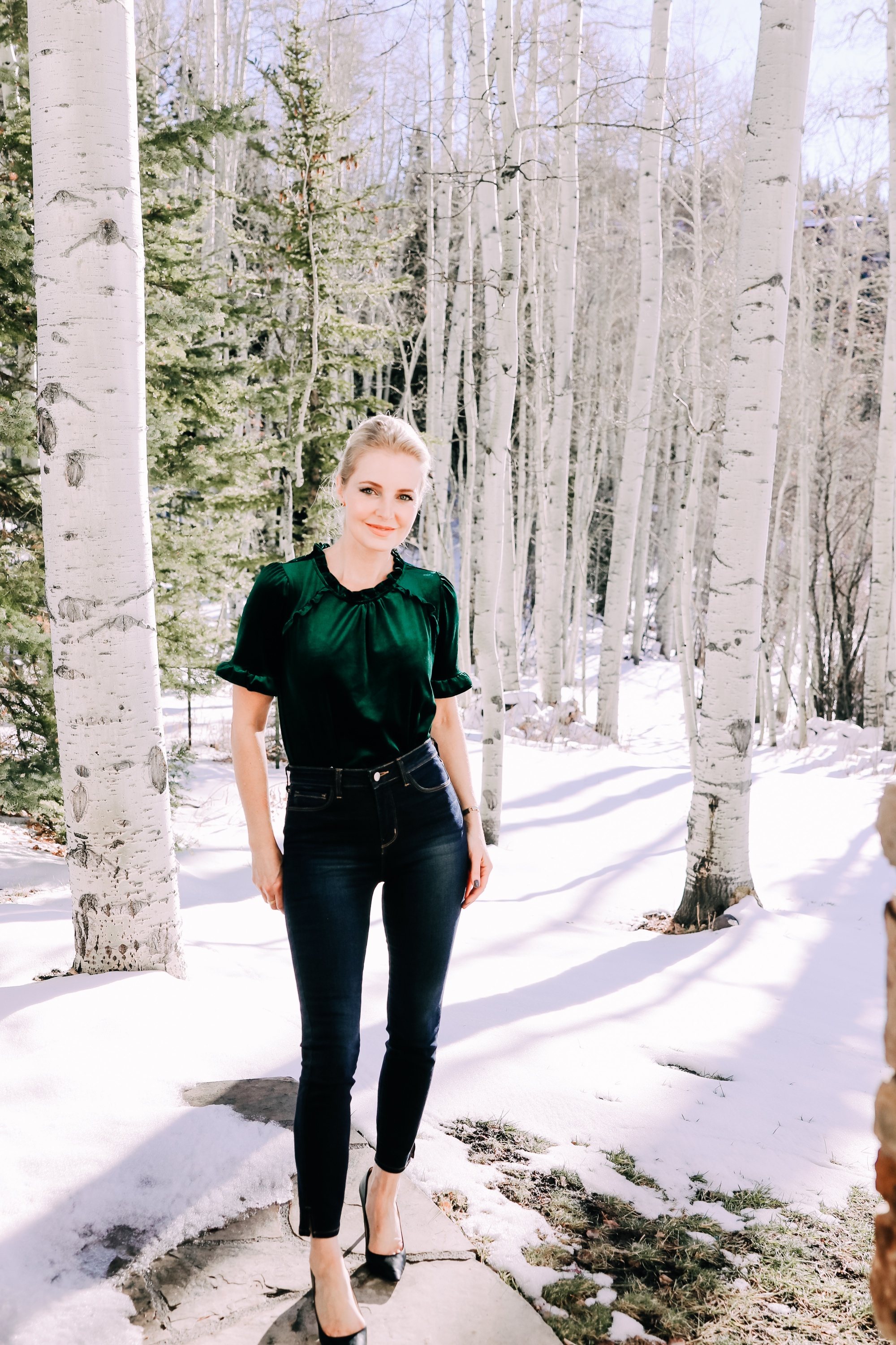 Holiday Outfits With Jeans, Erin Busbee of Busbee Style wearing a green velvet ruffle sleeve blouse by Gibson, L'Agence dark wash skinny jeans, and black Jimmy Choo Romy pumps from Nordstrom outside in the snow in Telluride, Colorado