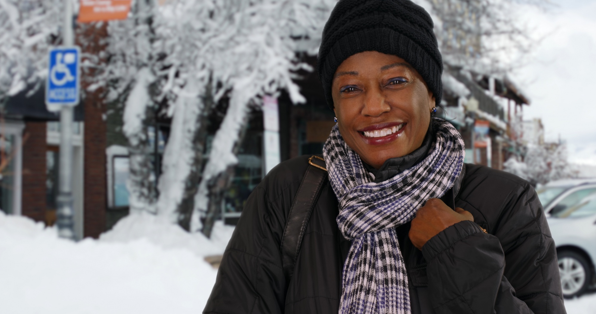 benefits of being outside during winter, Black woman in a black hat and jacket on a snowy sidewalk