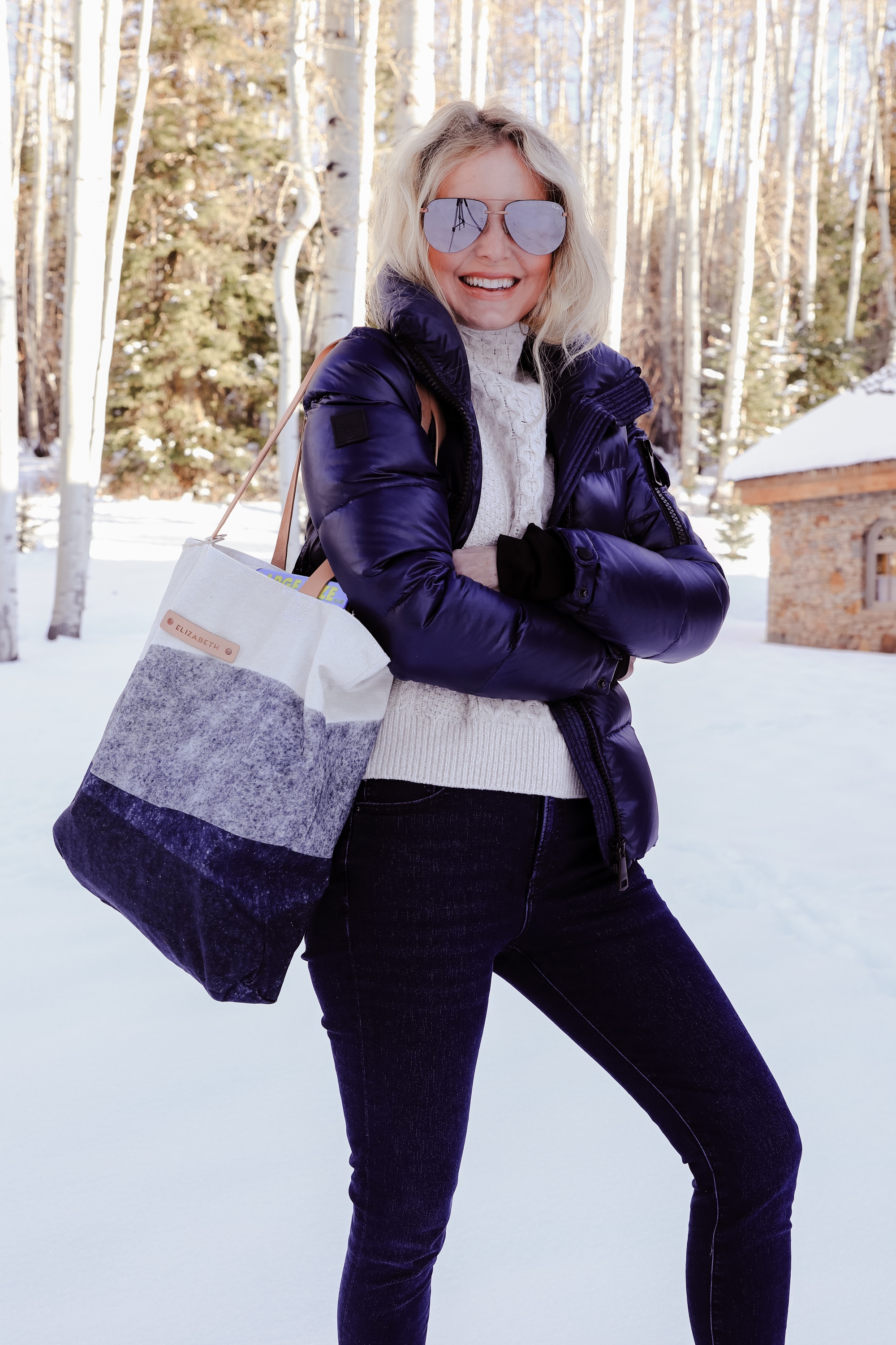 Personalized Gifts, Erin Busbee of Busbee Style carrying a blue and white personalized tote bag from Minted wearing a SAM. puffer jacket with a cable knit sweater and jeans in Telluride, Colorado