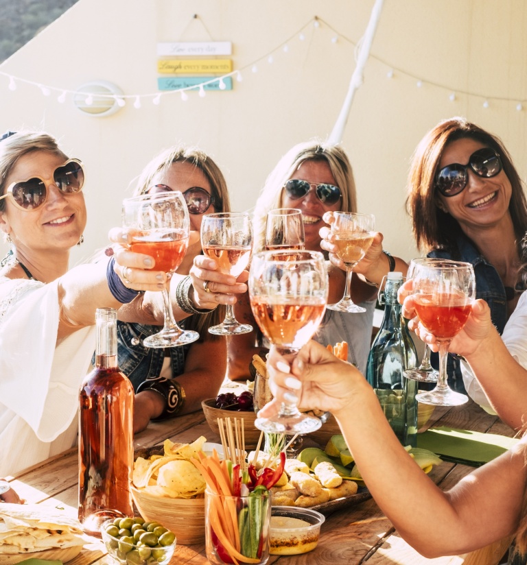 fun girls getaways, group of women friends toasting glasses of wine on vacation