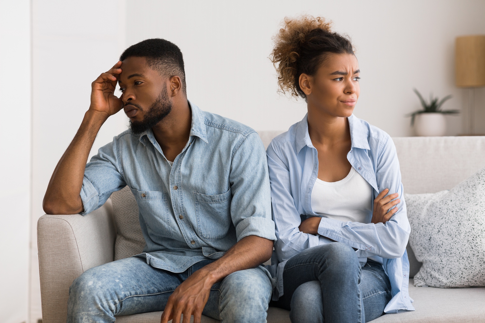 Toxic relationship habits, African American couple sitting on the sofa looking away from each other in anger