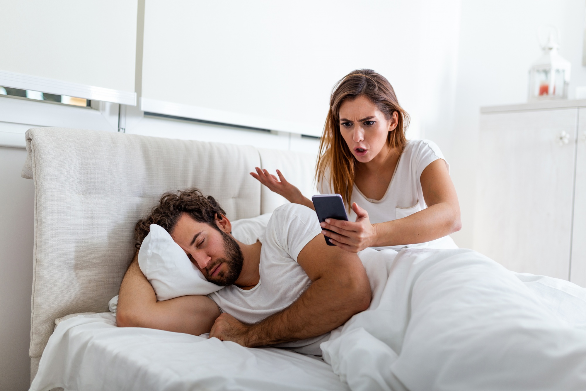 Toxic relationship habits, husband sleeping while his wife is checking text messages on his cell phone