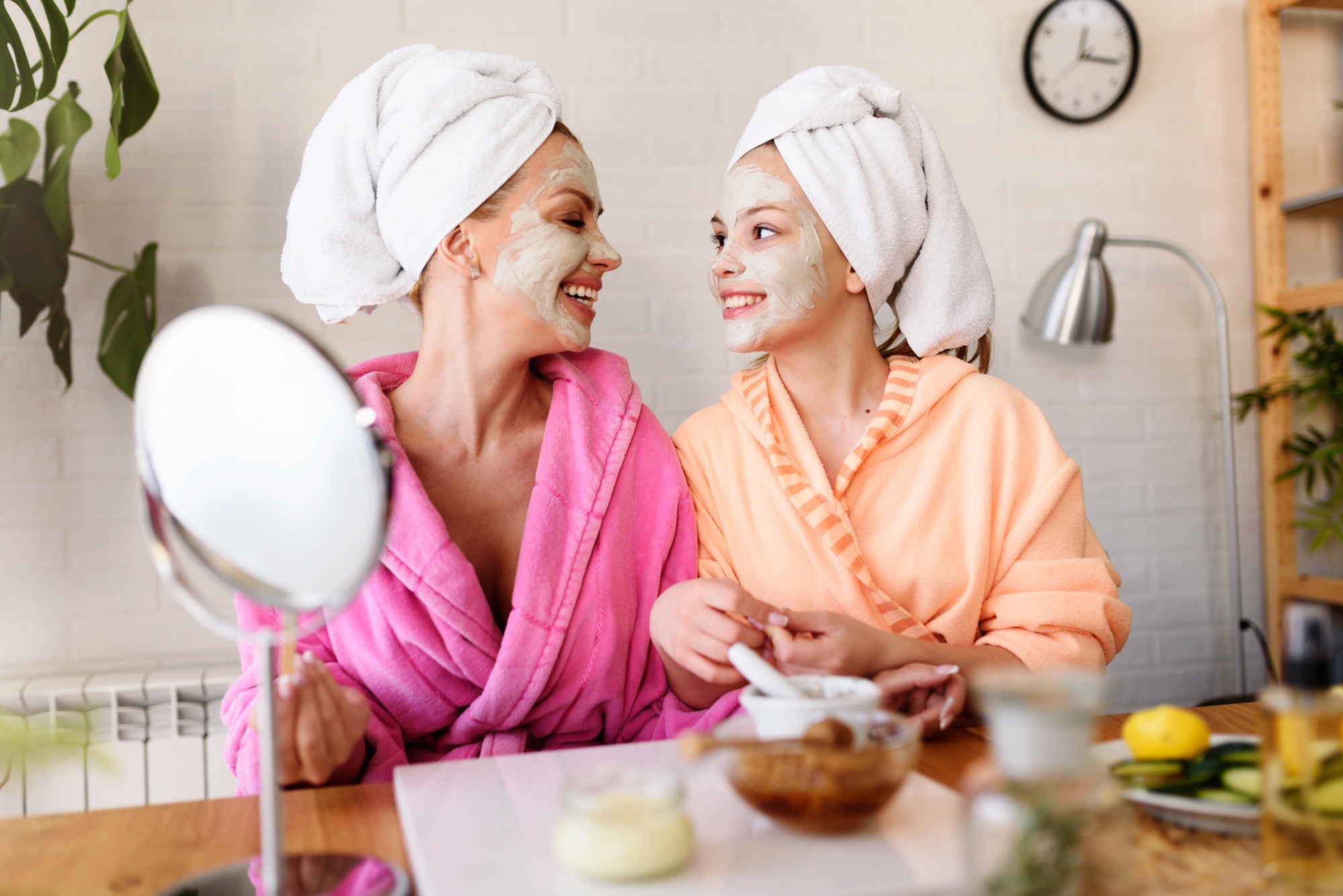 Mother daughter spa day, mom and daughter in bathrobes and towels using natural cosmetics and having fun at home