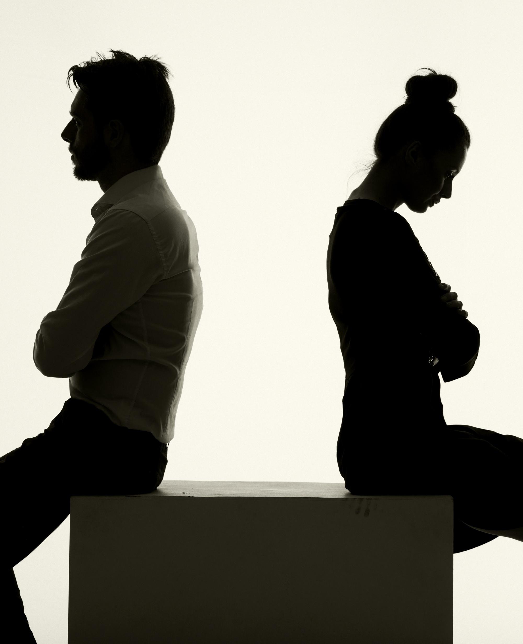 Toxic relationship habits, silhouette of man and woman sitting back to back in an argument