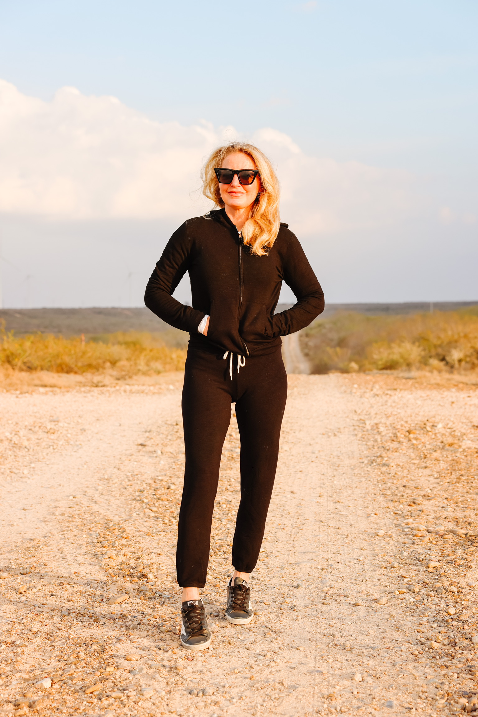 Cozy Loungewear, Erin Busbee of Busbee wearing a black hoodie by Monrow over a white long sleeve tee by Free People tucked into black drawstring joggers by Monrow and black Golden Goose sneakers in south Texas