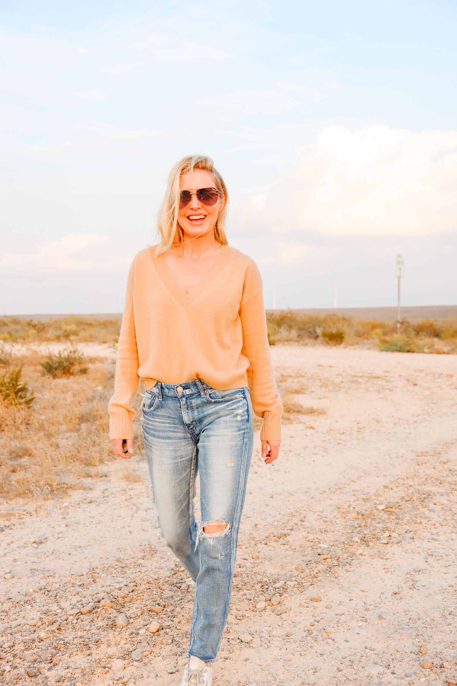 elevated basics, Erin Busbee of Busbee wearing a camel cashmere v-neck sweater from INtermix with distressed skinny jeans by Moussy Vintage and white golden goose sneakers in south Texas