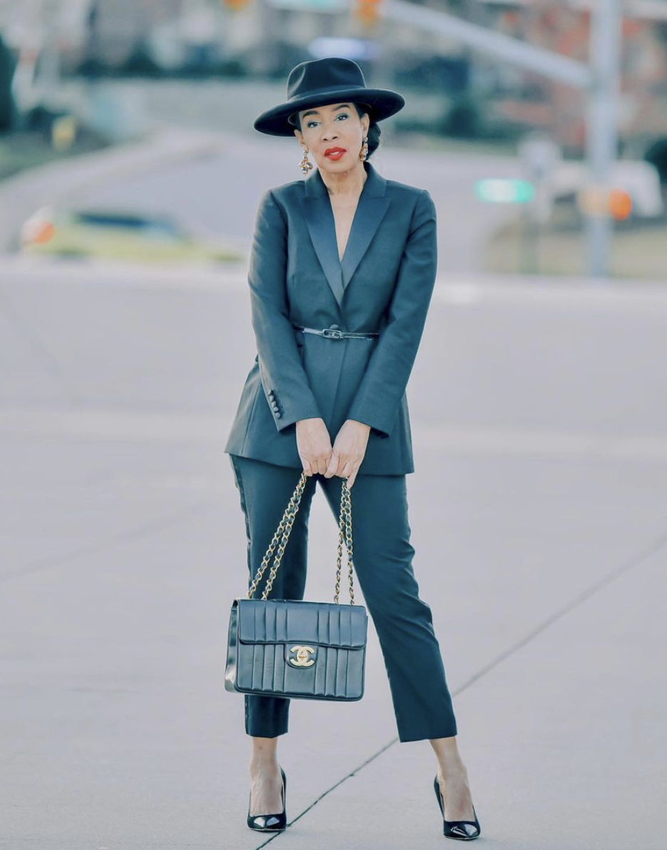 Styling Blazers Over 40, Stephanie from Haute Grey Fox wearing a belted blazer with black trousers, black pumps, a black hat, and black Chanel bag